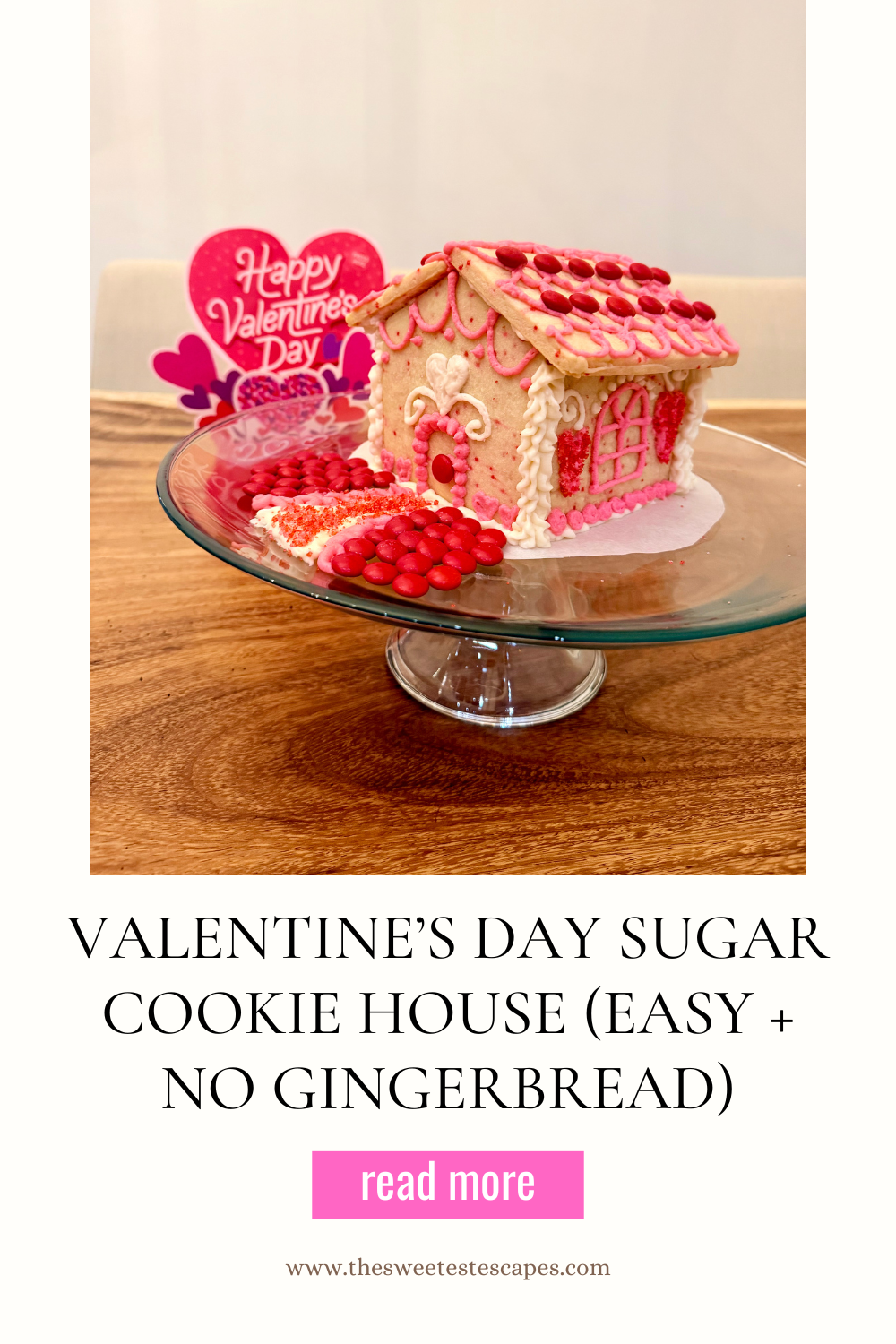 Valentine’s Day sugar cookie house decorated with pink buttercream frosting, heart candies, and festive Valentine sprinkles.