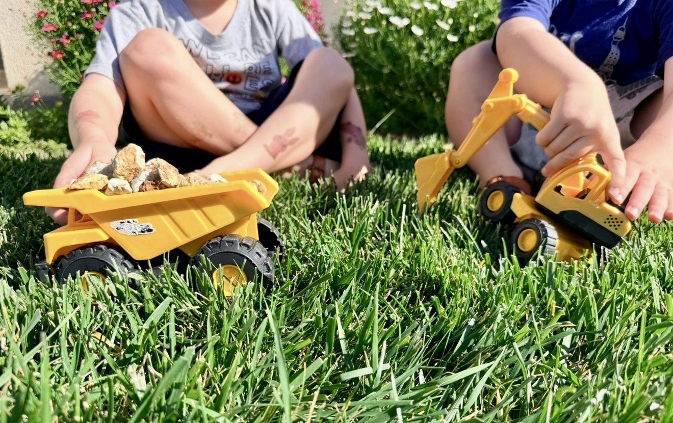 Backyard Earth Day activity for kids using toy trucks to clean up rocks and play outside