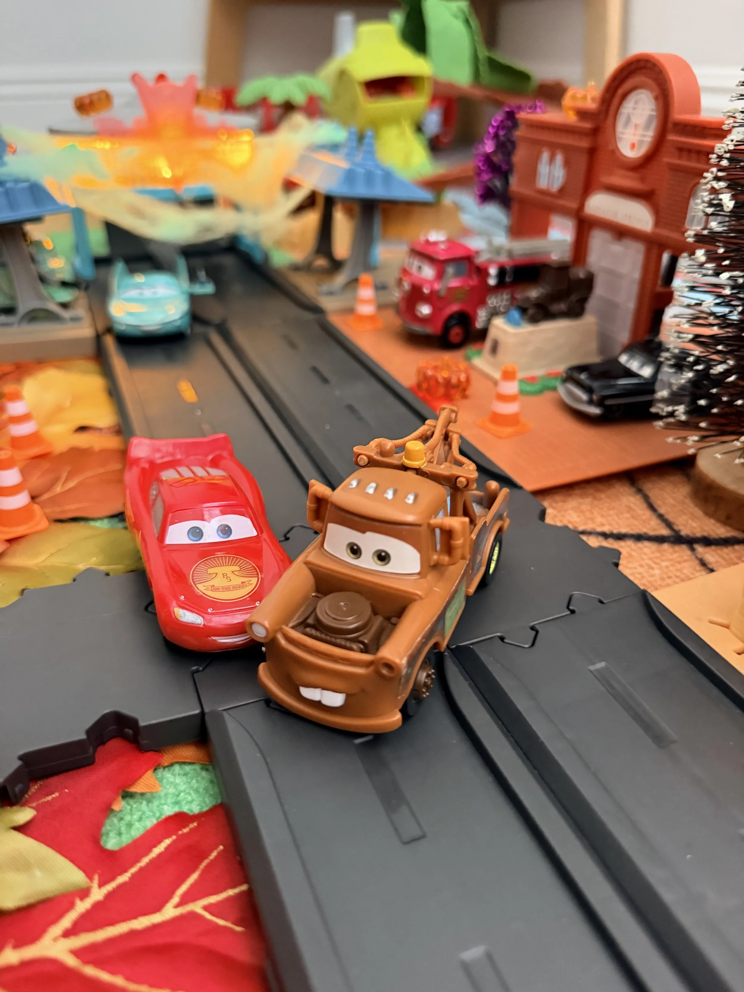 Lightning McQueen and Mater on the road in a Halloween Radiator Springs playset decorated with fall leaves, spiderwebs and miniature trees.