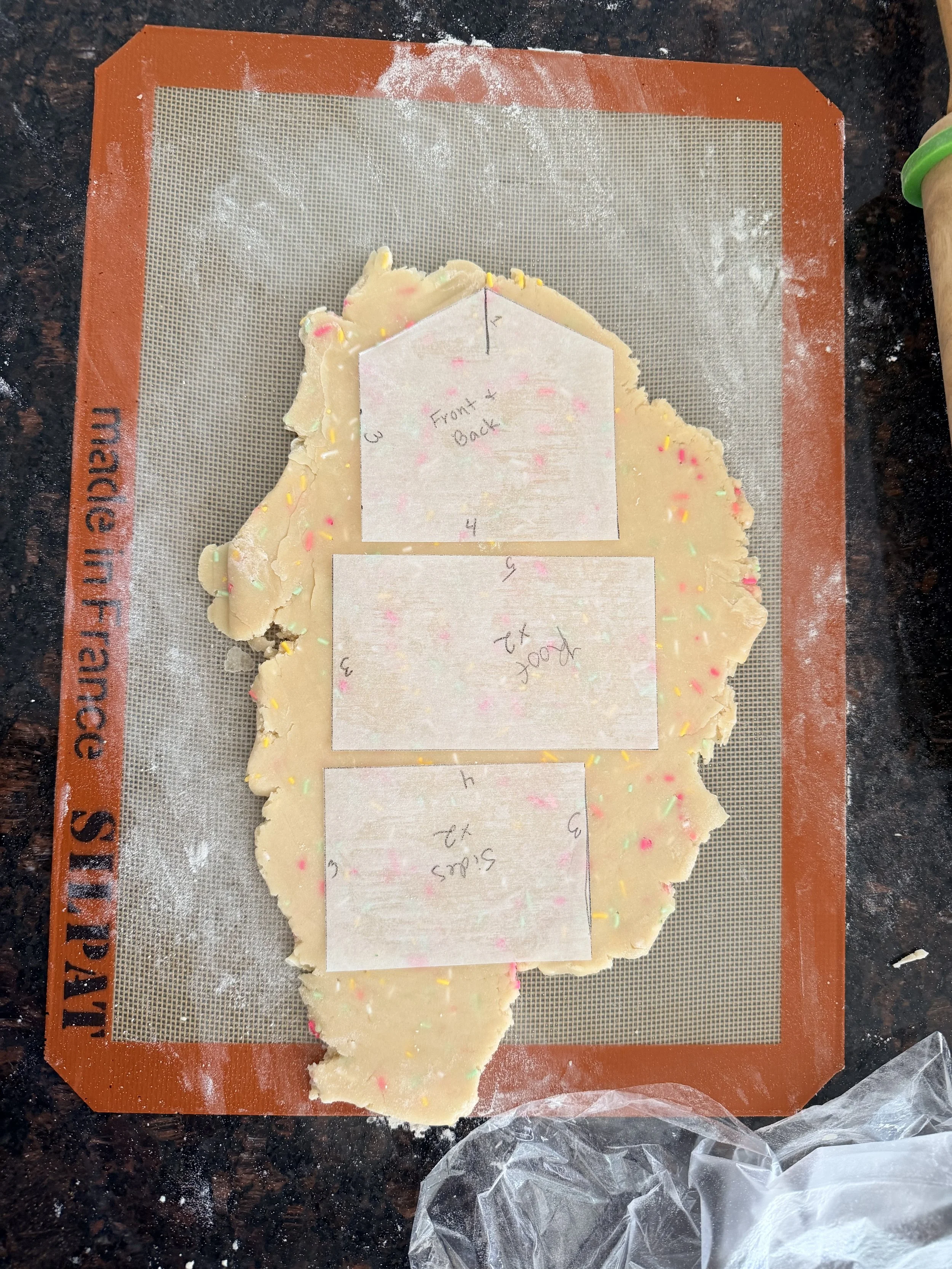 Printable sugar cookie house template placed on rolled confetti cookie dough before baking.