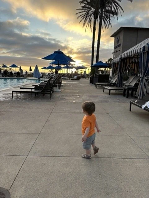 toddler walking around the Carlsbad Hilton Pool at sunset