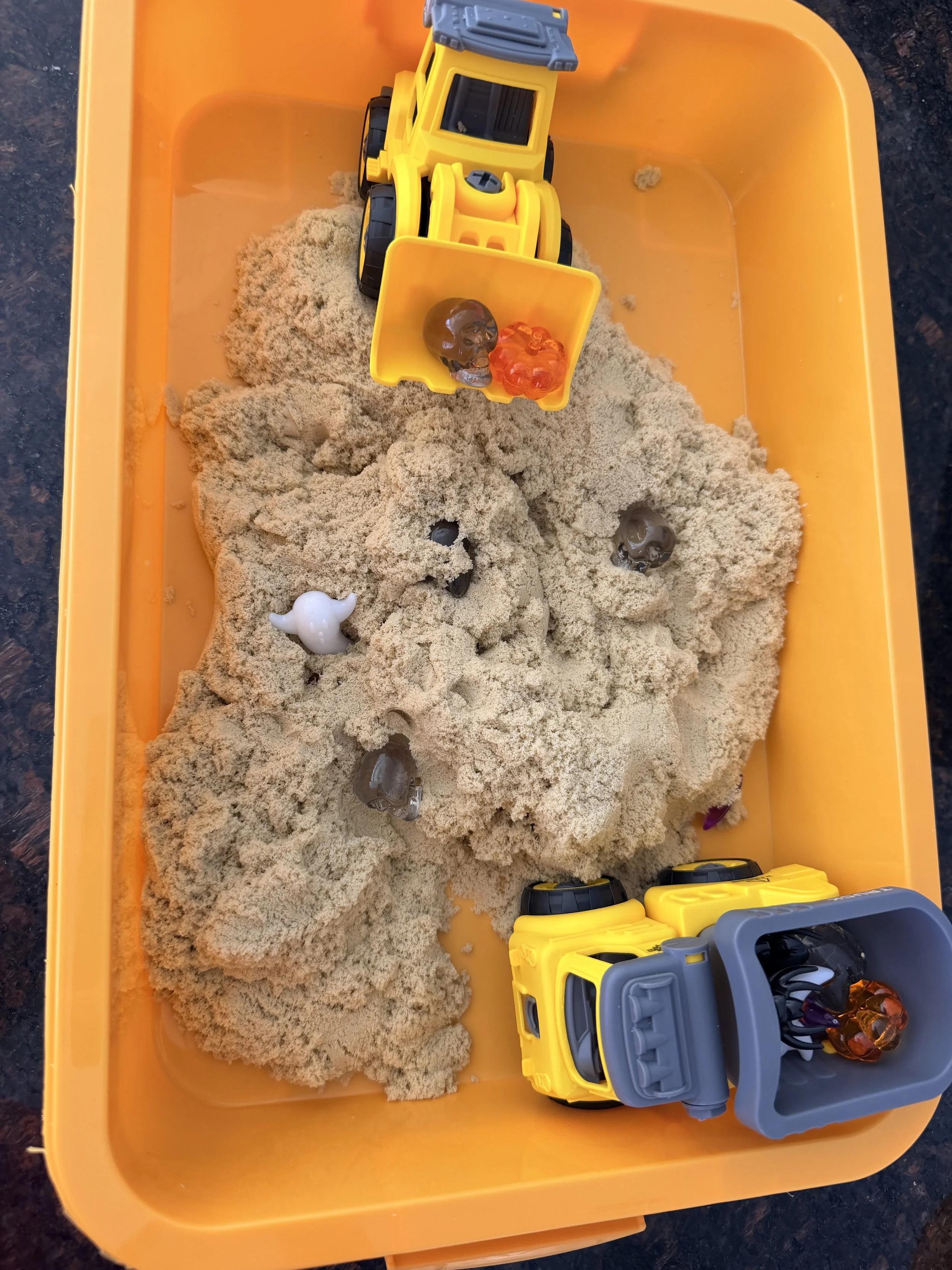 Use kinetic sand and trucks to dig for Halloween treasure