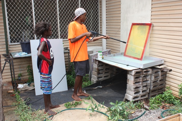  Mikey Gurruwiwi cleaning his screen after printing with Gadaman Yunupingu looking on.  