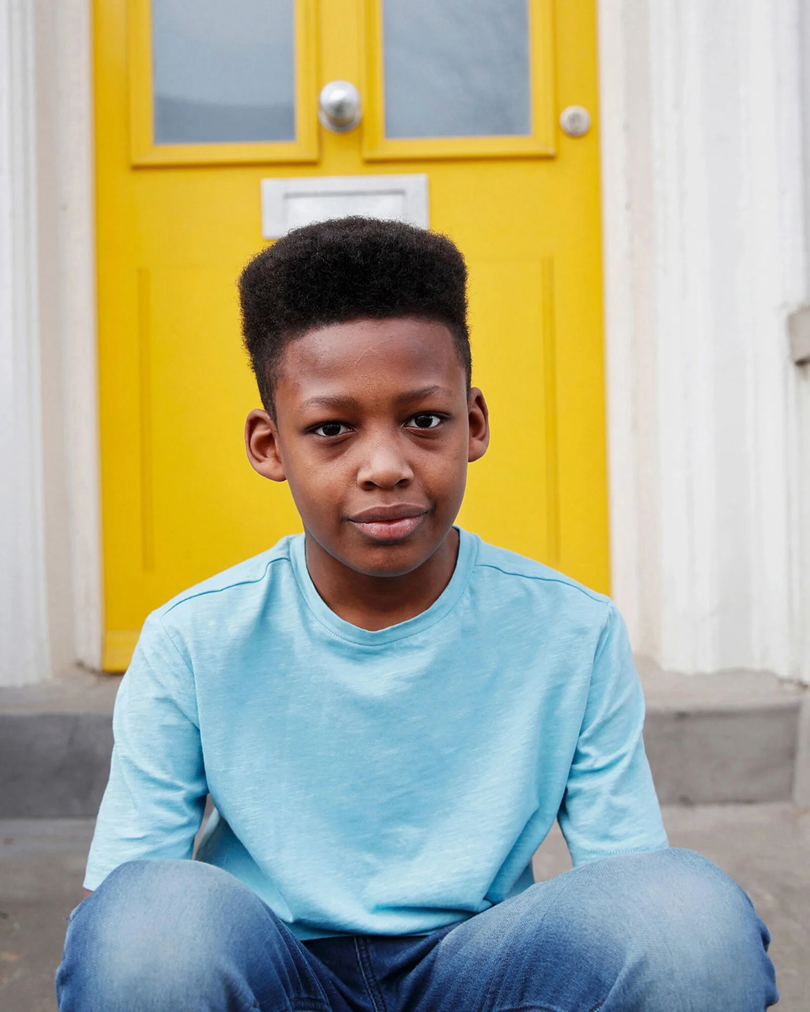 portrait-of-a-boy-sitting-outside-his-home.jpeg