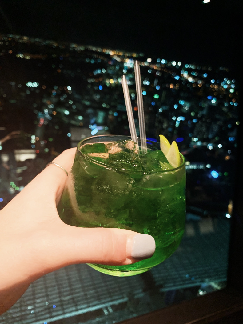 woman holding a drink at the Sky Tower one of the places to eat in Auckland