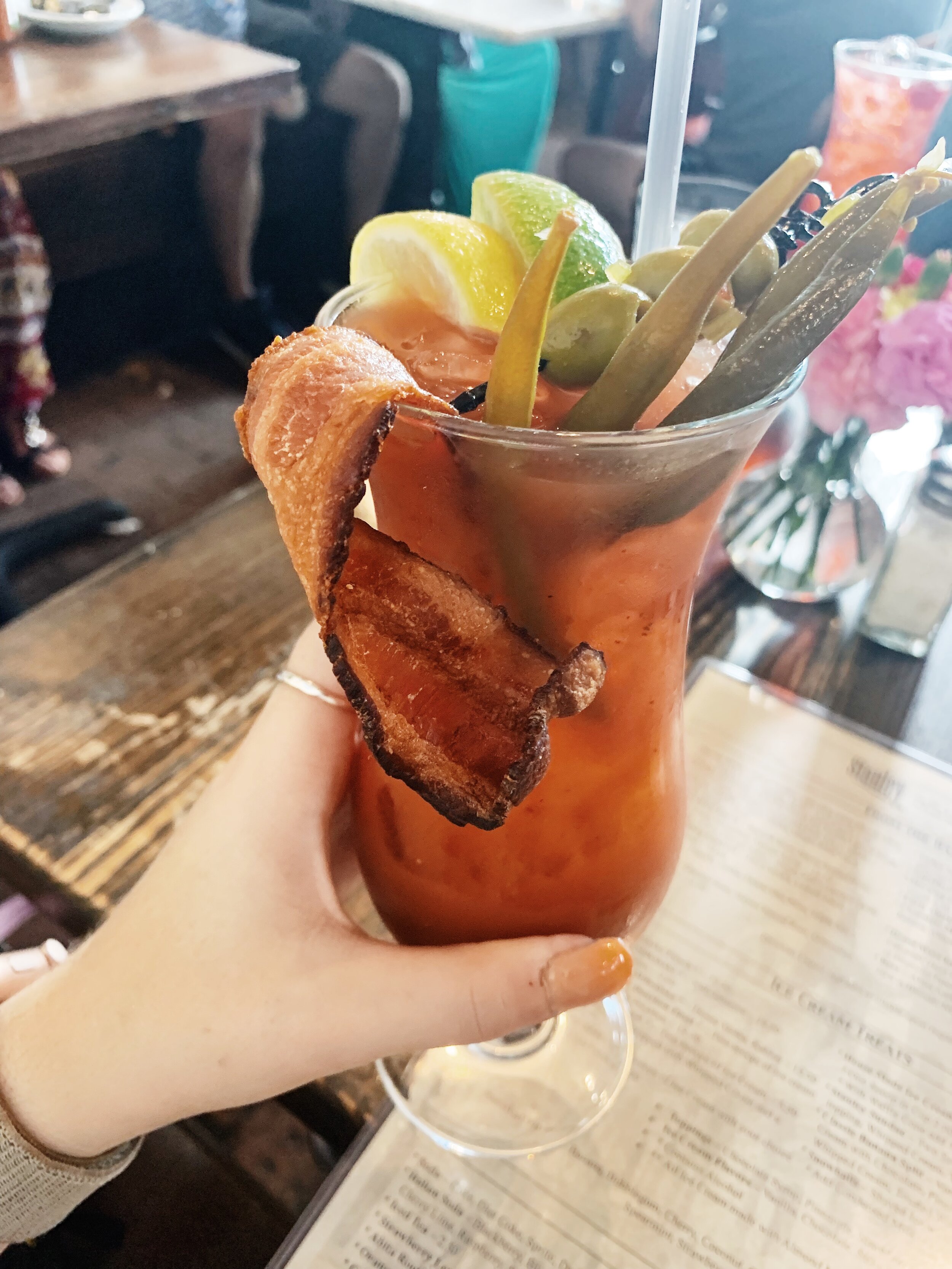 woman holding a drink with bacon