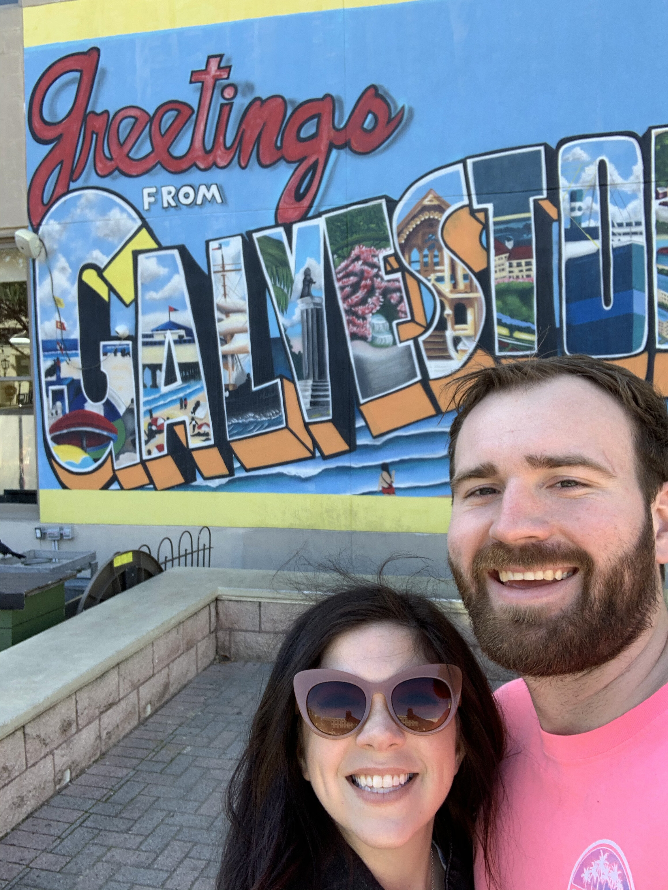 a couple taking a selfie with a Galveston mural