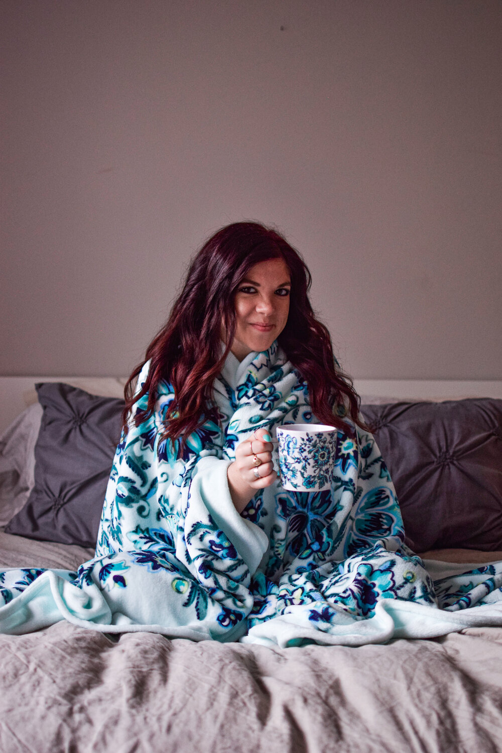 woman sitting cozy and holding a mug in her bed and sharing to be successful