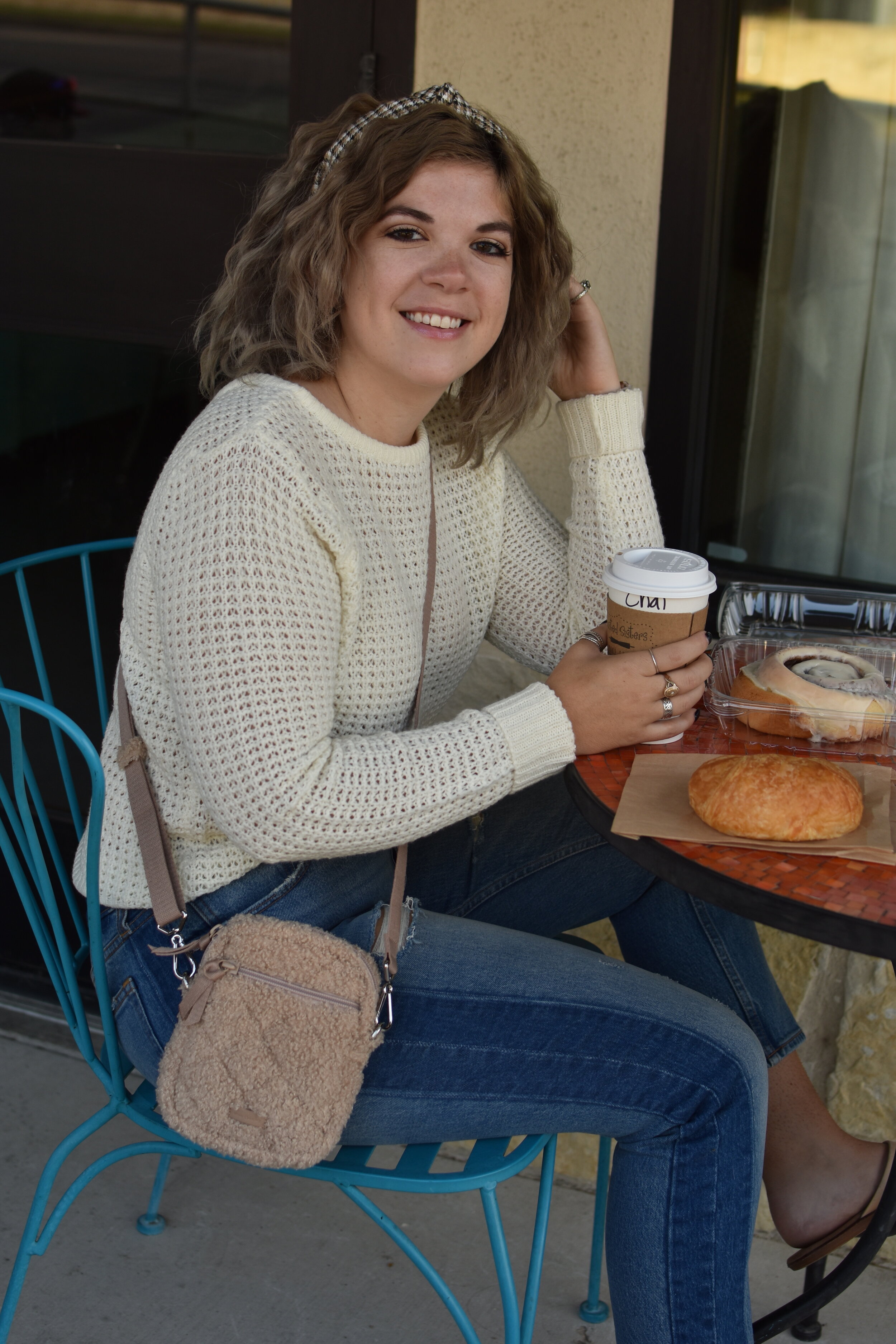 woman holding a cup to-go outside a cafe