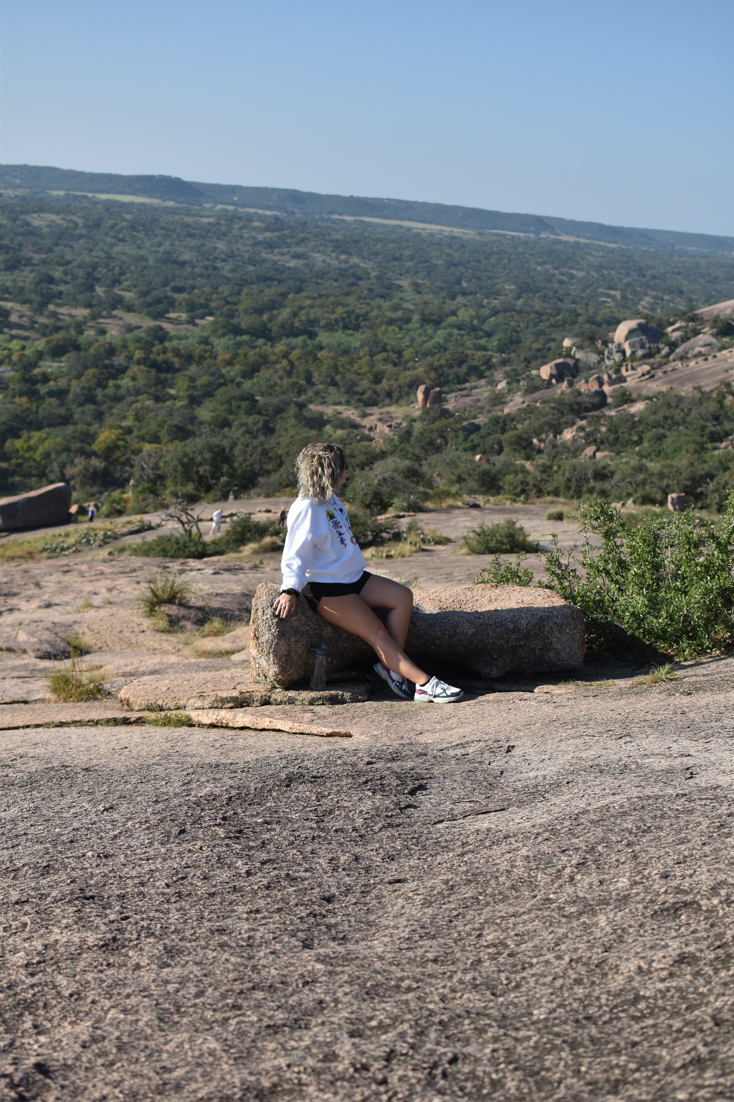 woman sitting on a rock with a view at Enchanted Rock
