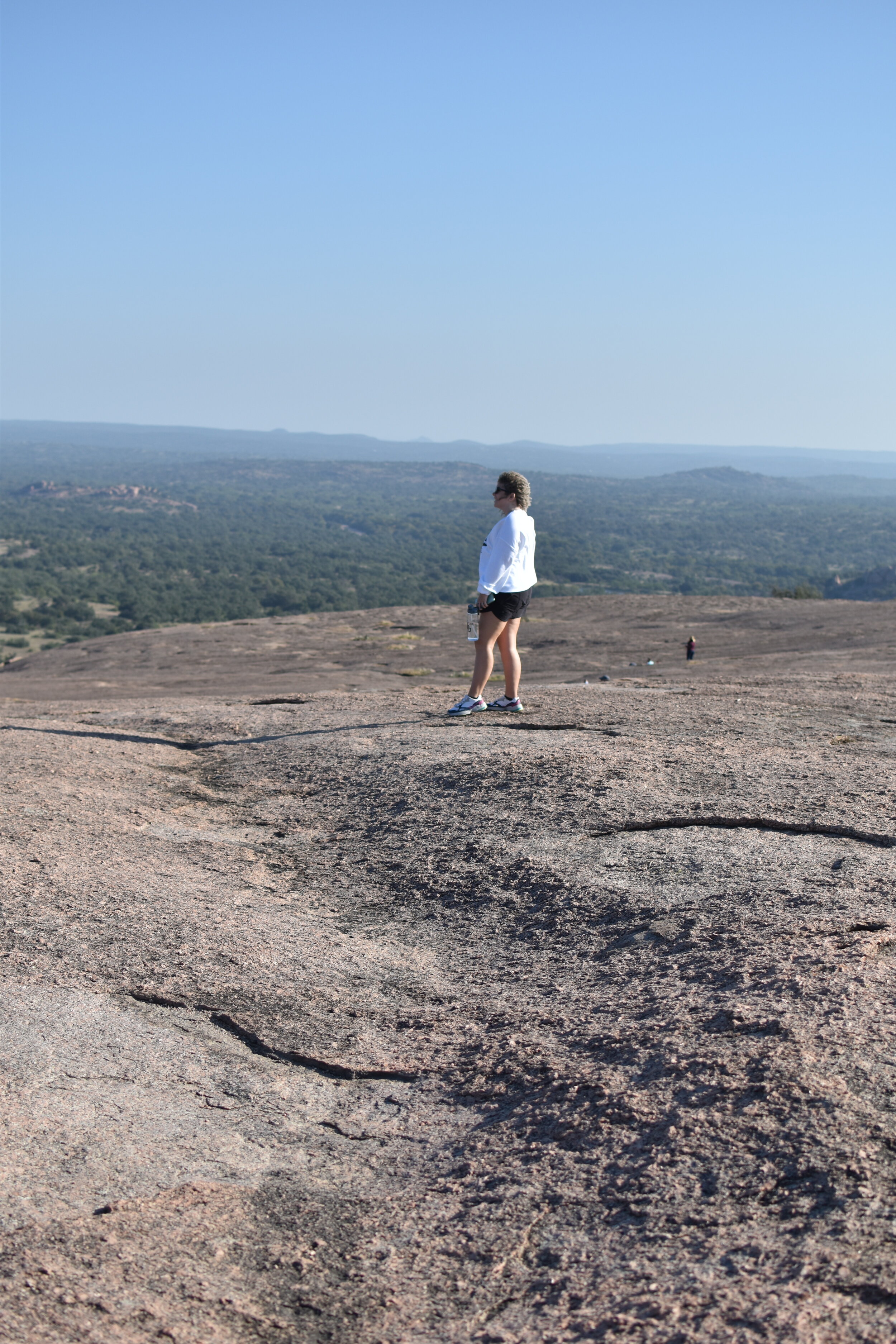 woman standing on a plan rock at the Enchanted Rock