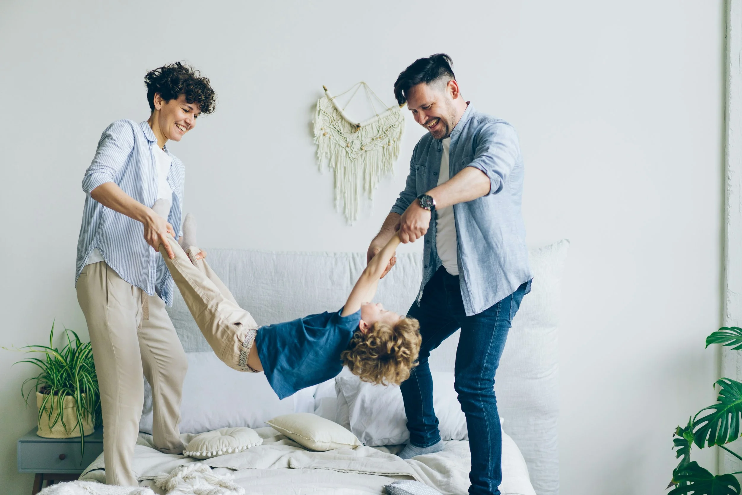 Parents laugh and play with their young son at home, the kind of joyful connection family counseling helps restore
