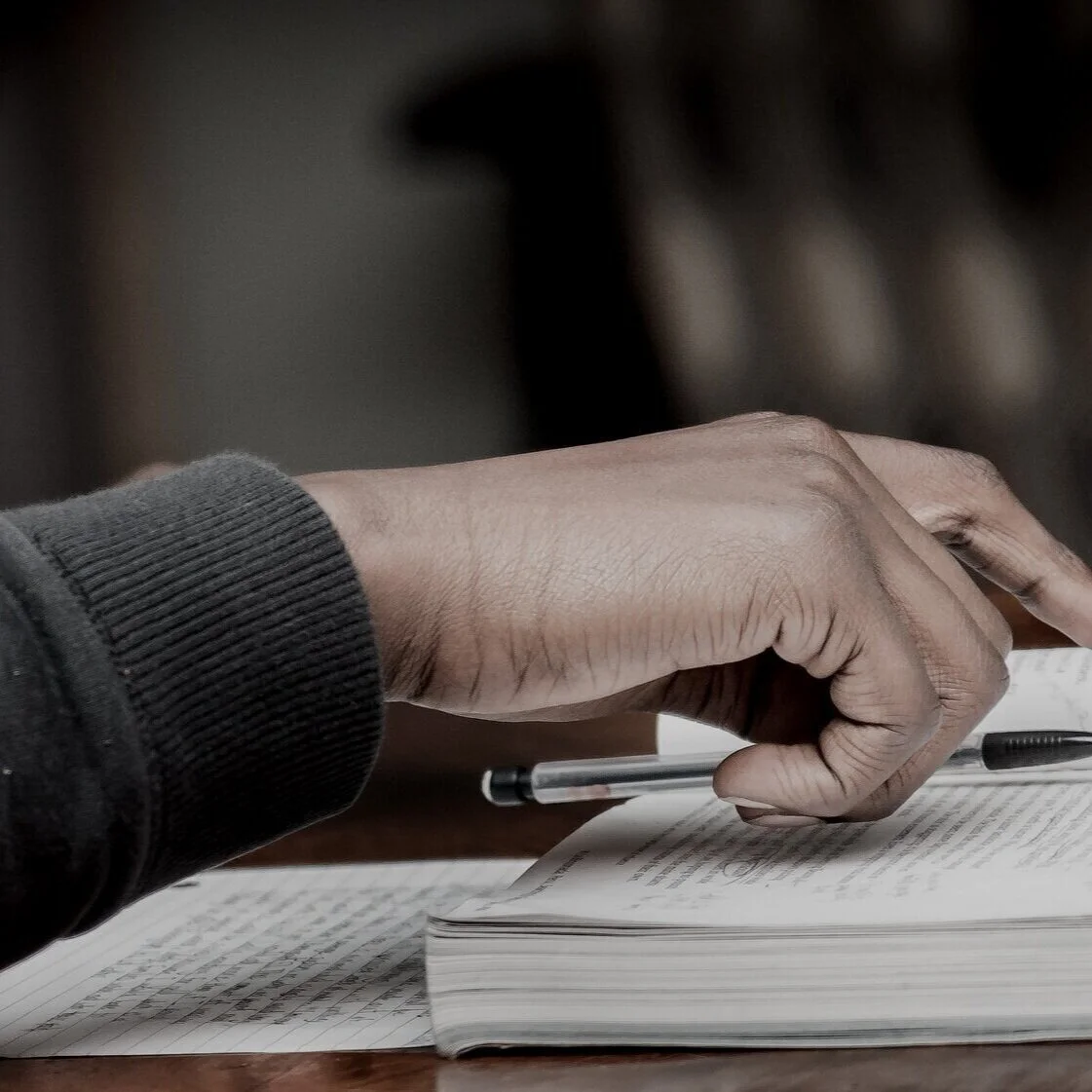 A hand holding a pencil taking notes from a book