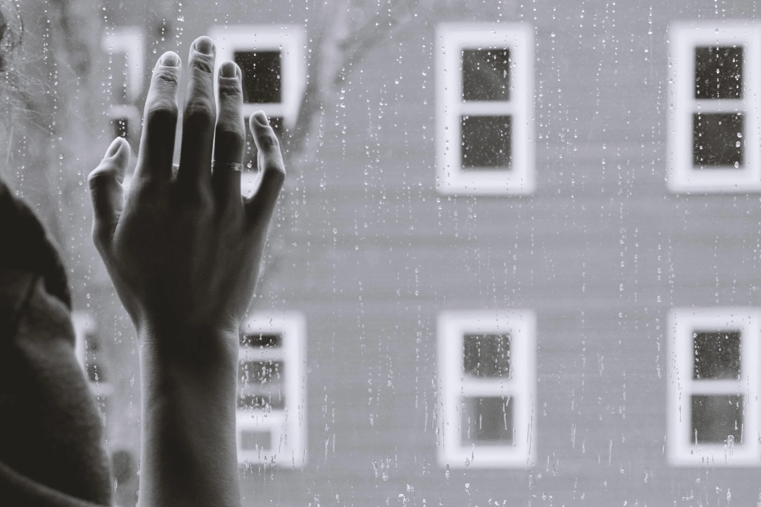 A hand on a window while it is raining outside in Houston, Texas