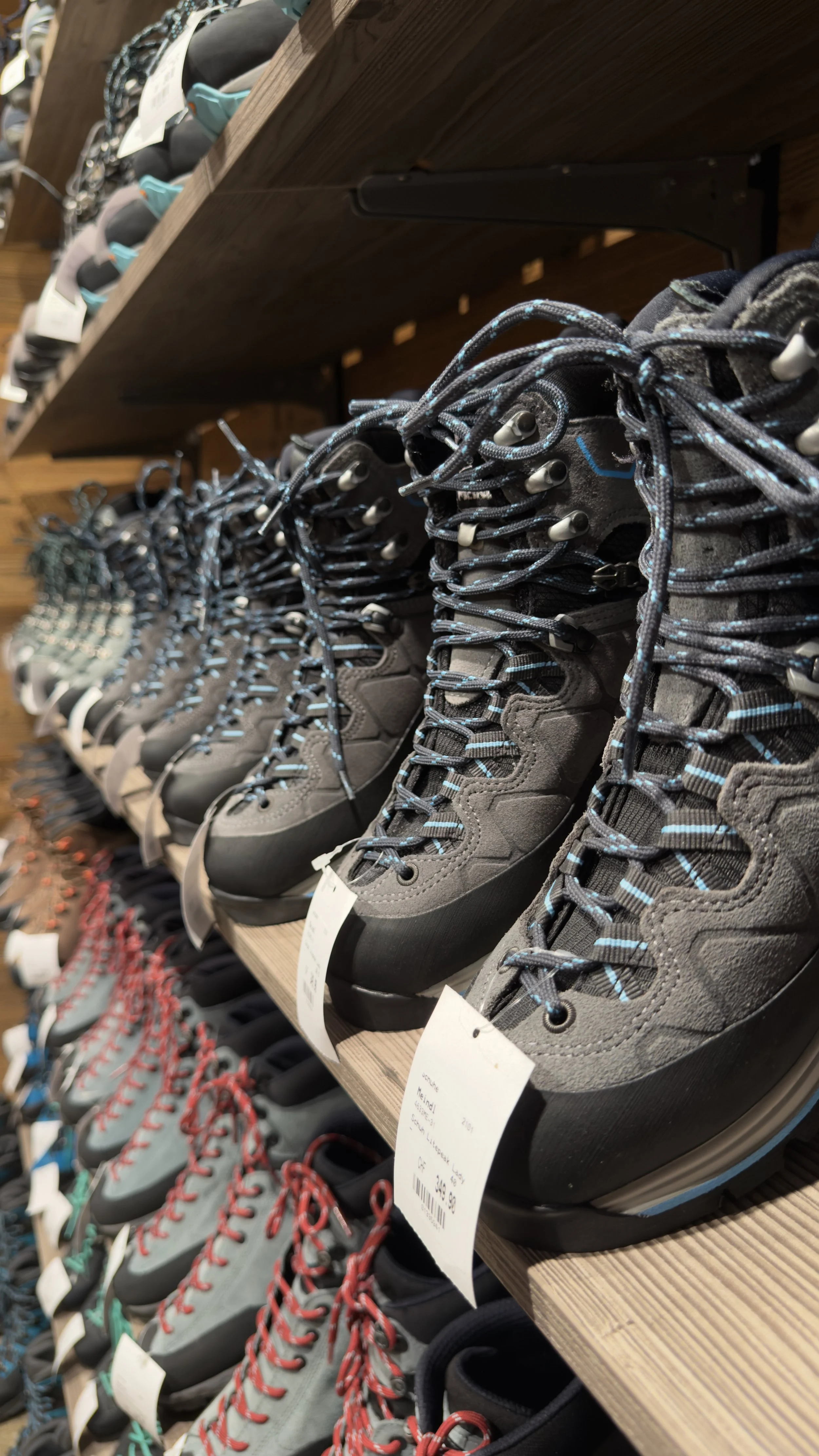 Various hiking boots in a shoe store, arranged on wooden shelves.