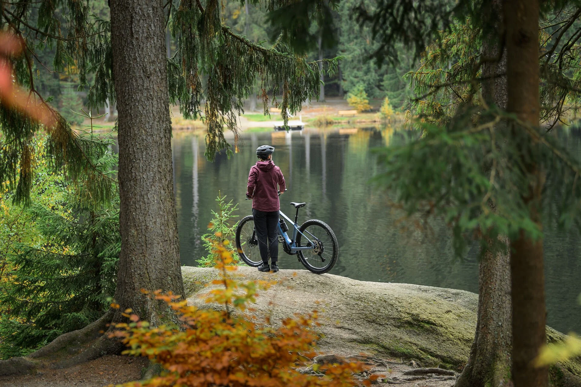 Person mit Mountainbike am See im Engadin, umgeben von Waldlandschaft und ideal für Bike-Touren ab St. Moritz.