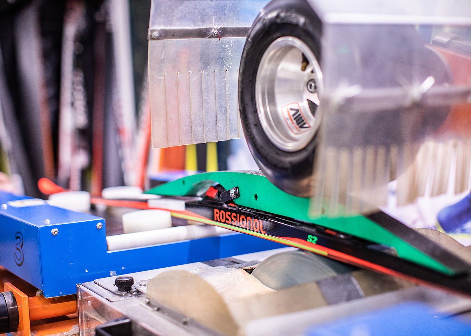 Close-up of a mechanical machine featuring a black timing belt, a metal pulley, and various electrical components, including a blue box labeled with the number 3.