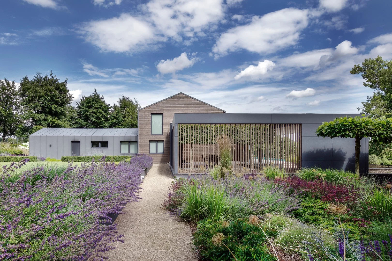 The Farmer’s House acts as the UK base for AR Design Studio’s clients, who return to the English countryside from their travels to tend to their farmstead. Set on a private estate in the most western part of the South Downs National Park, the house’s rural location is its raison d’etre. AR Design Studio were approached by the clients who were looking to add a completely self-contained yet joined annexe, that would be a space for their children and grandchildren to ‘take over’ when they were staying. The team at AR Design Studio proposed an extension and makeover that would wrap everything together in a unified and elegant form. The old and new are joined by a glazed link that sits between the existing house and the new annexe. The annex, which sits to the east, is surrounded by a large covered alfresco dining and relaxing area. The terrace and pool sat centrally in front of the house are tied in with a large sweeping canopy above. This reaches around the existing house, and continues to the west of the plot, providing an additional sheltered seating space. This canopy incorporates openings for the existing trees and partial shading elements, providing protection to the southern facing façade with delicate timber louvres. Visually, the extension appears as a single mass placed on the landscape, with the snug, kitchen/living and dining space, utility room, and two of 3 bedrooms on the ground floor. Small punctuations have been made into the timber cladding to introduce natural light, yet their scale kept modest to protect the rooms from the on looking driveway. The geometry of the façade is clad with fibre cement and provides the dining area with more privacy. The hidden subterranean mass below avoids a visual bulk which could otherwise swamp the existing house’s proportions, and includes a bedroom, plant room and garage space for 2 cars. — “We thoroughly enjoyed working with AR Design, it has been a great experience, the completed project has exceeded our expectations and improved our home immeasurably, the quality of the design and the attention to detail throughout have been exceptional, thank you!” Chris Chapman - Client