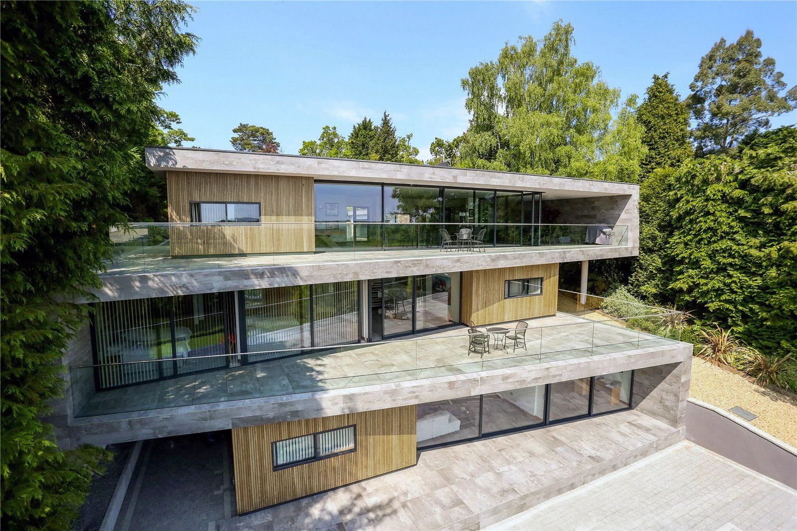 Inspired by the site context and defining character, the intention of Folding House was to minimise the impact on the location and surrounding scenery by embedding the house into the hill side. The concept began with an existing ‘zig zag’ pathway. This path was then continued in the form of a folding, solid ribbon, creating habitable spaces between the plans. Solid timber boxes were inserted in between where private space was required, with the remaining space offering open plan living with a connection to the expansive balconies and stunning views beyond. The accommodation is split over three floors with the upper floor situated at ground level. The lower two floors stagger down the site following the gradient of the landscape and taking the user towards the lower garden and river. The ground floor layout contains most of the required open plan living accommodation with stunning views of the River Avon. The lower ground floor constitutes of bedroom accommodation and is connected to the upper floor via a feature staircase and lift. The garden level floor comprises a mixture of bedrooms and living accommodation that spill out onto a generous terrace and path down to the river.