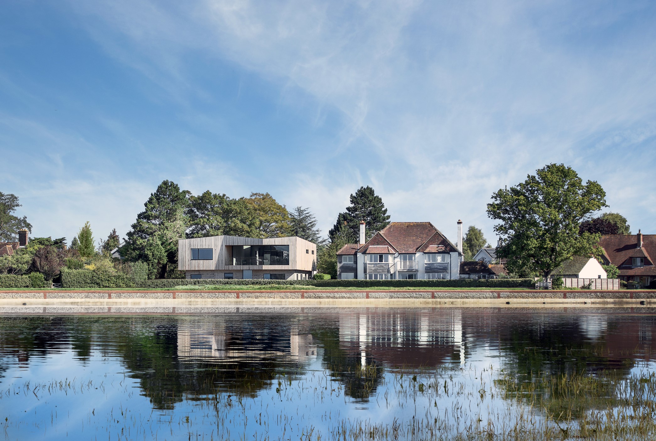 Creek House is a private bespoke new build house located in Bosham, West Sussex, completed in the summer of 2018 by Winchester based architects AR Design Studio. The clients, passionate about design and longstanding active members of the community, came to AR Design Studio in 2015 with a vision for their life-time home in the village. The clients saw potential in this prime location on the periphery of the Bosham estuary, and despite difficult planning constraints, the client’s contemporary vision combined with AR Design Studio’s experience set out to achieve a sensitive design appropriate to the idyllic setting. The site is set within the Chichester Harbour Area of Outstanding Natural Beauty and Bosham Conservation Area, striving to protect and enhance the village’s traditional character and significant history. The team at AR, with an extensive water front portfolio, worked closely with both Chichester Harbour Conservancy and the planning department to achieve a sensitive design, but with the unconventional design and exposed site, the scheme attracted its share of public attention. The Creek House subtly draws influence from the geometries and materials of the sensitive context of Chichester, whilst achieving a contemporary design that undoubtedly challenges the vernacular of the area.