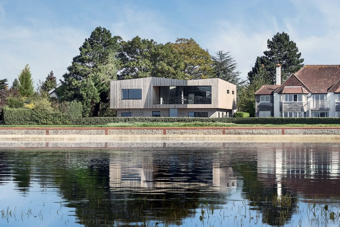 Creek House is a private bespoke new build house located in Bosham, West Sussex, completed in the summer of 2018 by Winchester based architects AR Design Studio. The clients, passionate about design and longstanding active members of the community, came to AR Design Studio in 2015 with a vision for their life-time home in the village. The clients saw potential in this prime location on the periphery of the Bosham estuary, and despite difficult planning constraints, the client’s contemporary vision combined with AR Design Studio’s experience set out to achieve a sensitive design appropriate to the idyllic setting. The site is set within the Chichester Harbour Area of Outstanding Natural Beauty and Bosham Conservation Area, striving to protect and enhance the village’s traditional character and significant history. The team at AR, with an extensive water front portfolio, worked closely with both Chichester Harbour Conservancy and the planning department to achieve a sensitive design, but with the unconventional design and exposed site, the scheme attracted its share of public attention. The Creek House subtly draws influence from the geometries and materials of the sensitive context of Chichester, whilst achieving a contemporary design that undoubtedly challenges the vernacular of the area.