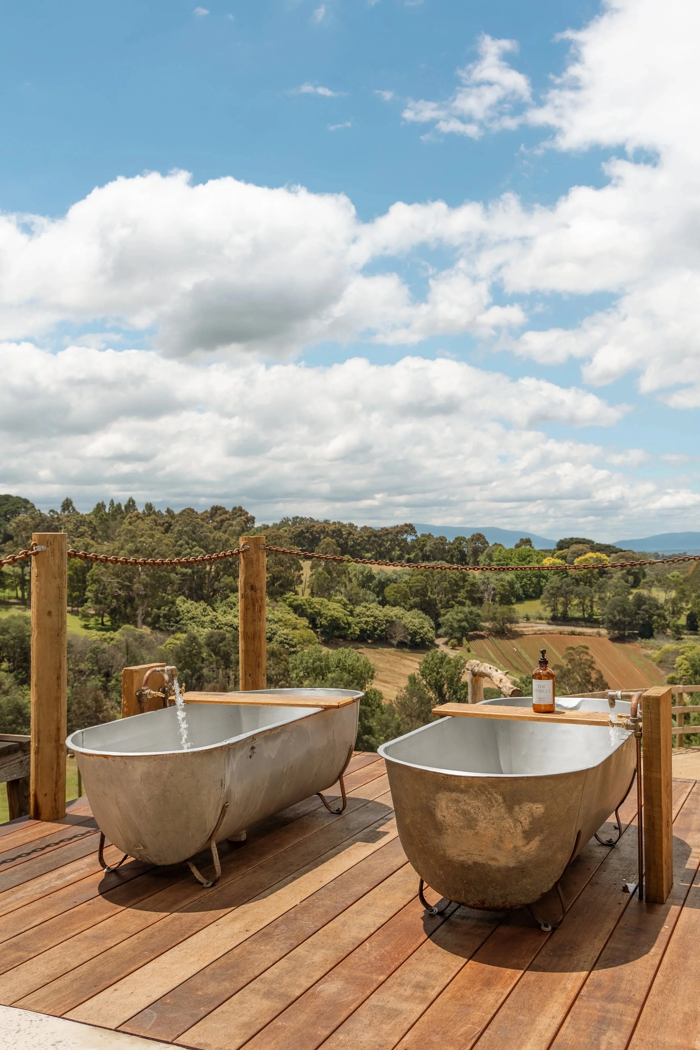 Twin outdoor bathtubs at Alkira Eco Glamping Safari in the Dandenong Ranges, Victoria, with stunning Warburton Ranges and rolling hill views. Romantic couples glamping and unique accommodation near Emerald, Puffing Billy and Melbourne.
