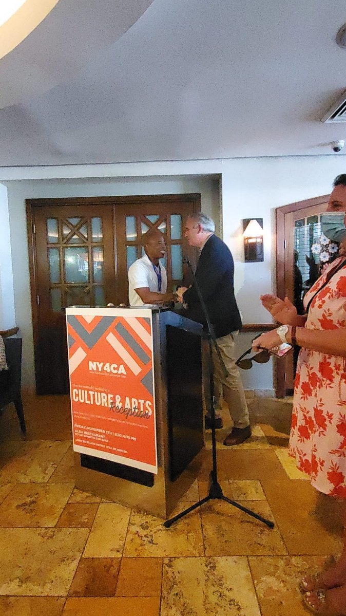  Eric Adams and John Calvelli shaking hands in front of a podium with a banner that reads “NY4CA Culture &amp; Arts Reception” 