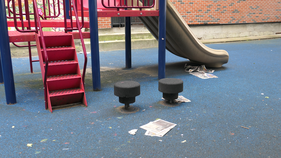 photo shows newspapers and trash by the childrens slide