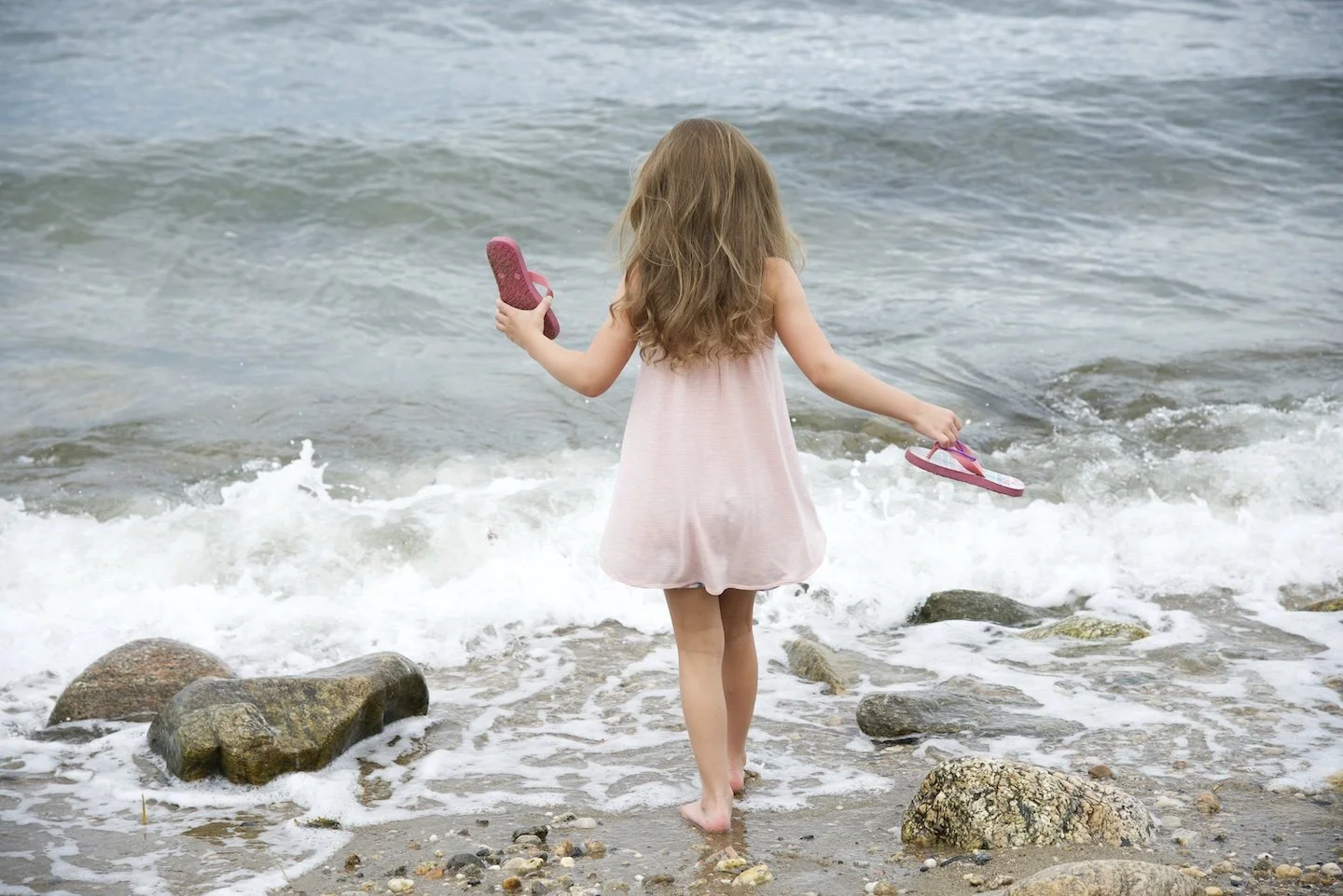 Girl wades into the water in Old Greenwich, Connecticut as photographer Pamela Einarsen takes candid photos