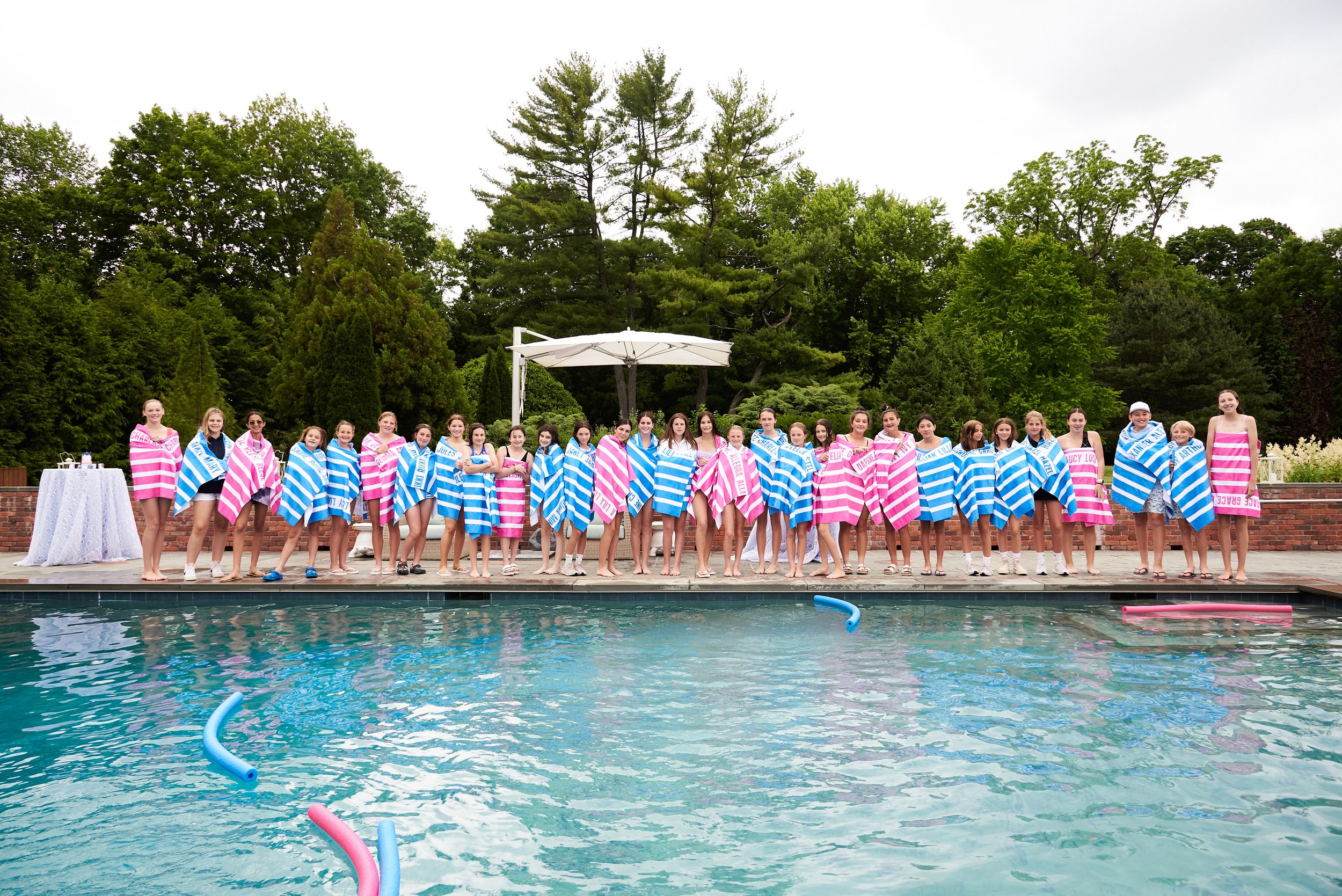 Teens stand in colorful towels at a pool party in Fairfield, CT, by event photographer Pamela Einarsen