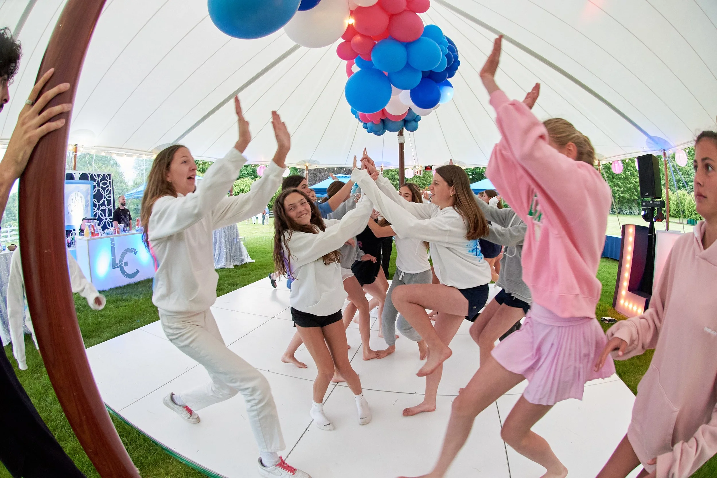 Girls dance under a tent with balloons at a bat mitzvah party in Fairfield, CT by event photographer Pamela Einarsen