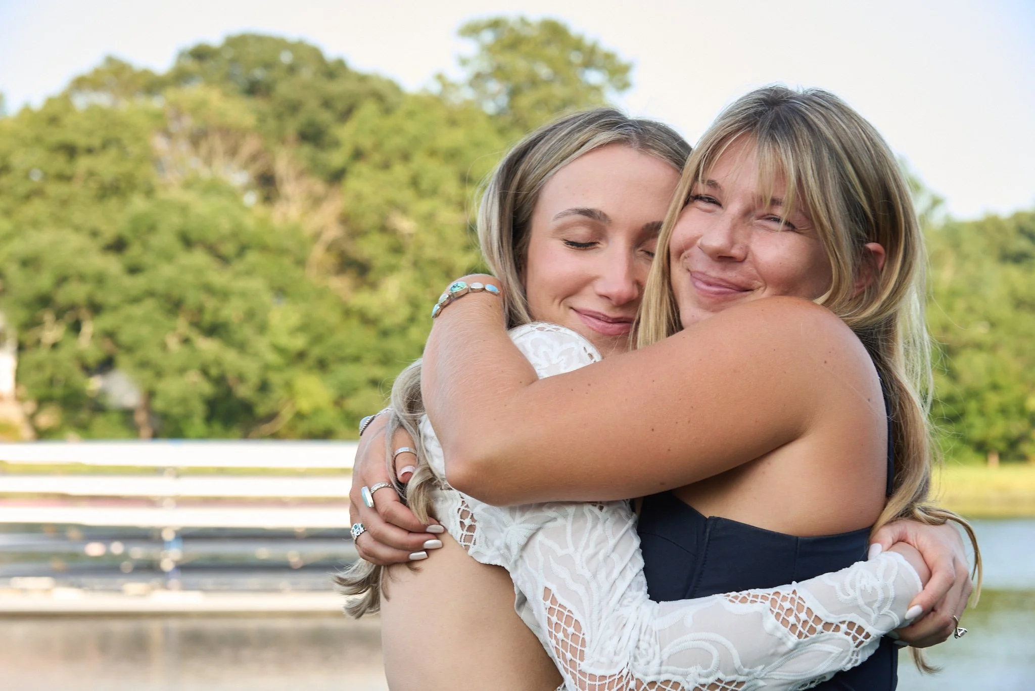 Bride is hugged by a friend at her wedding at the Saugatuck Rowing Club in Westport, CT, by event photographer Pamela Einarsen.