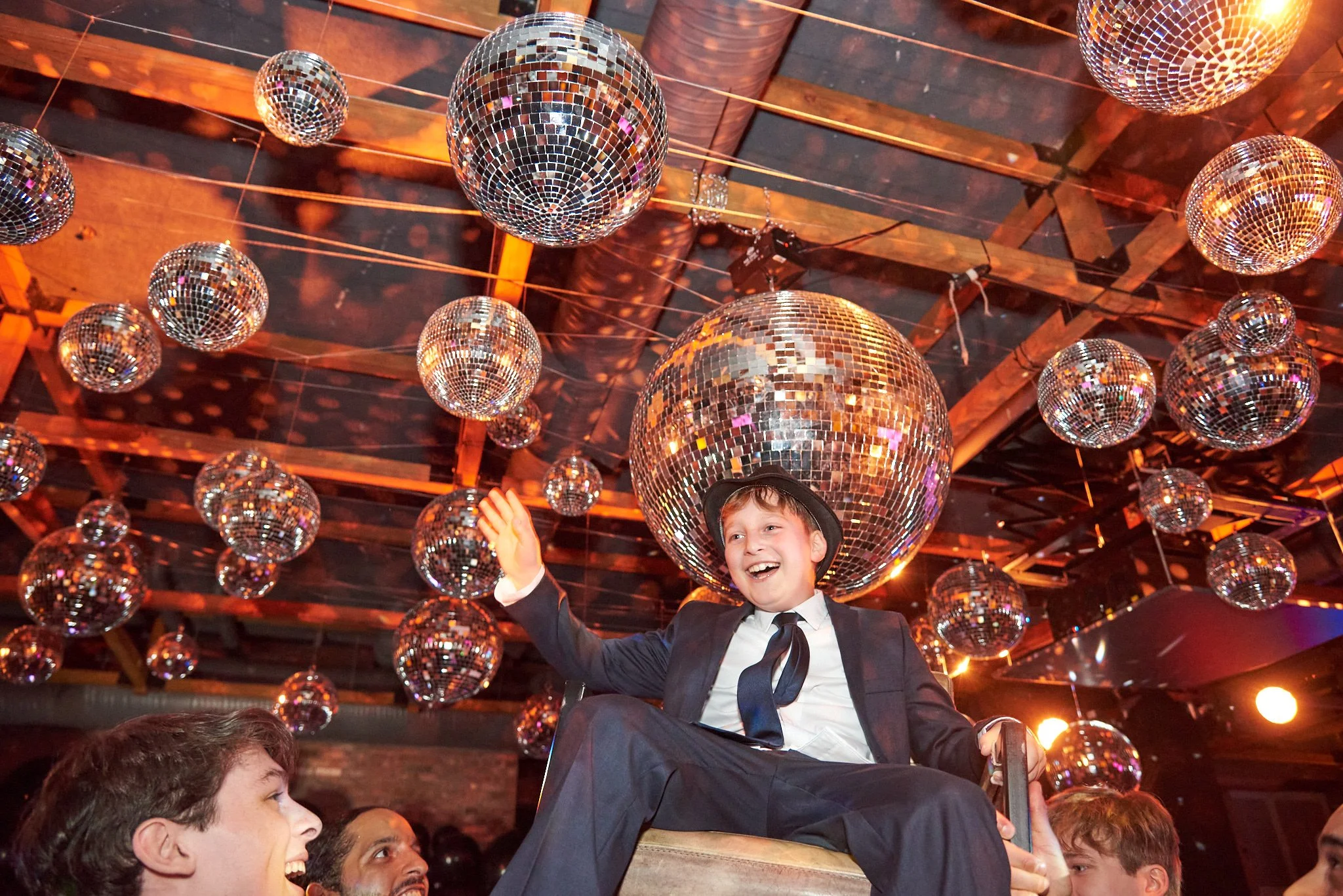 Boy lifted on chair at his sister’s bat mitzvah in NYC, captured by photographer Pamela Einarsen. 