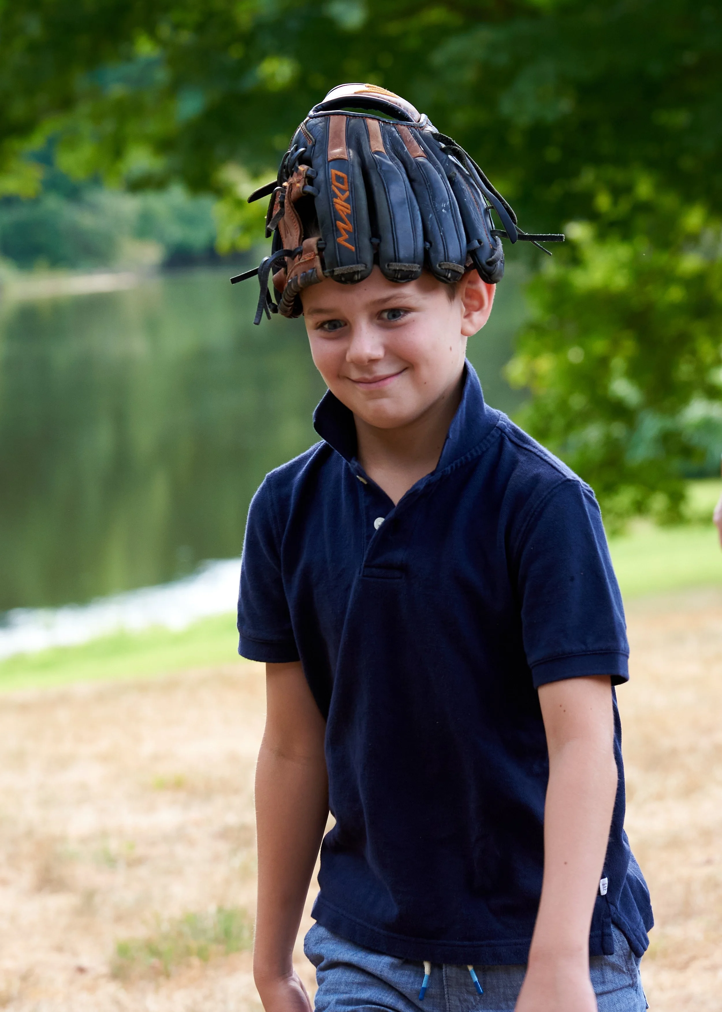Boy wears catchers mitt on his head at an extended family photo session with photographer Pamela Einarsen in Easton, CT.