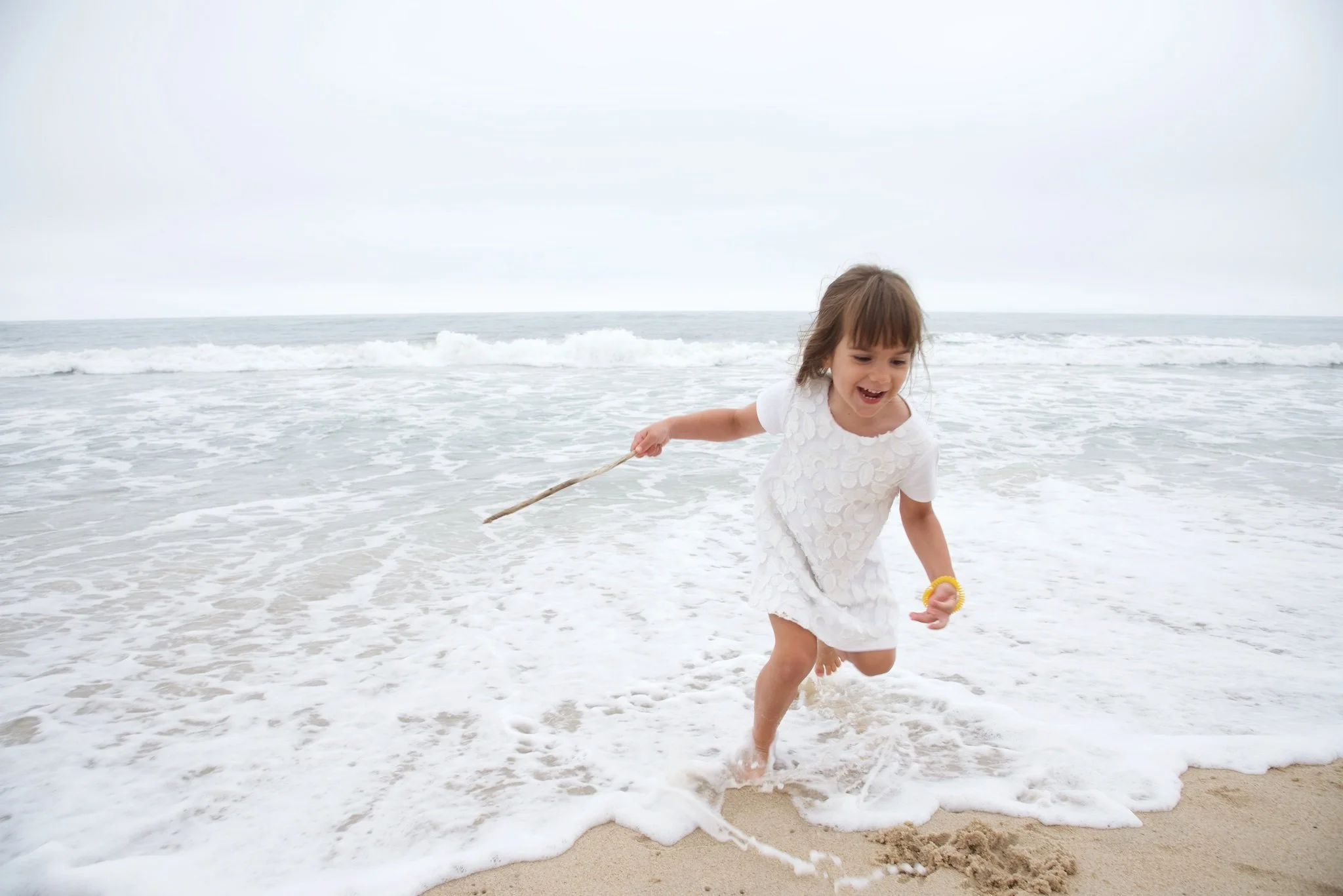 Girl plays in the waves in the Hamptons with family photographer, Pamela Einarsen.