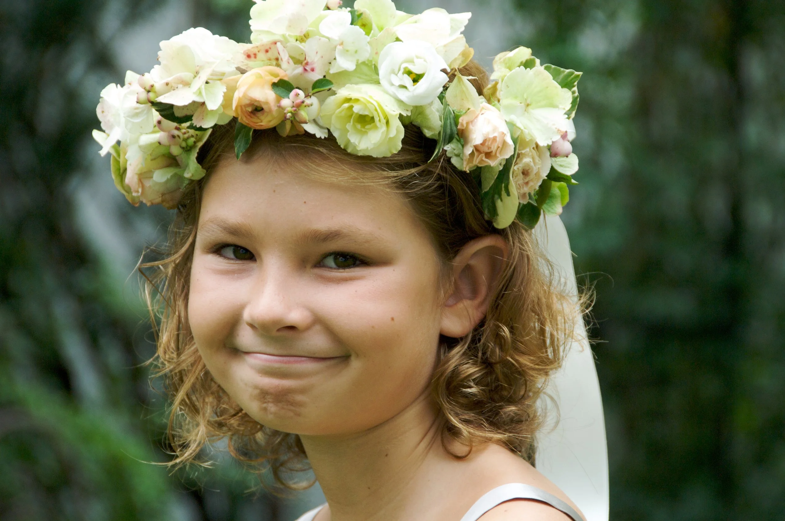 Flower girl smiles at outdoor wedding by event photographer Pamela Einarsen. 