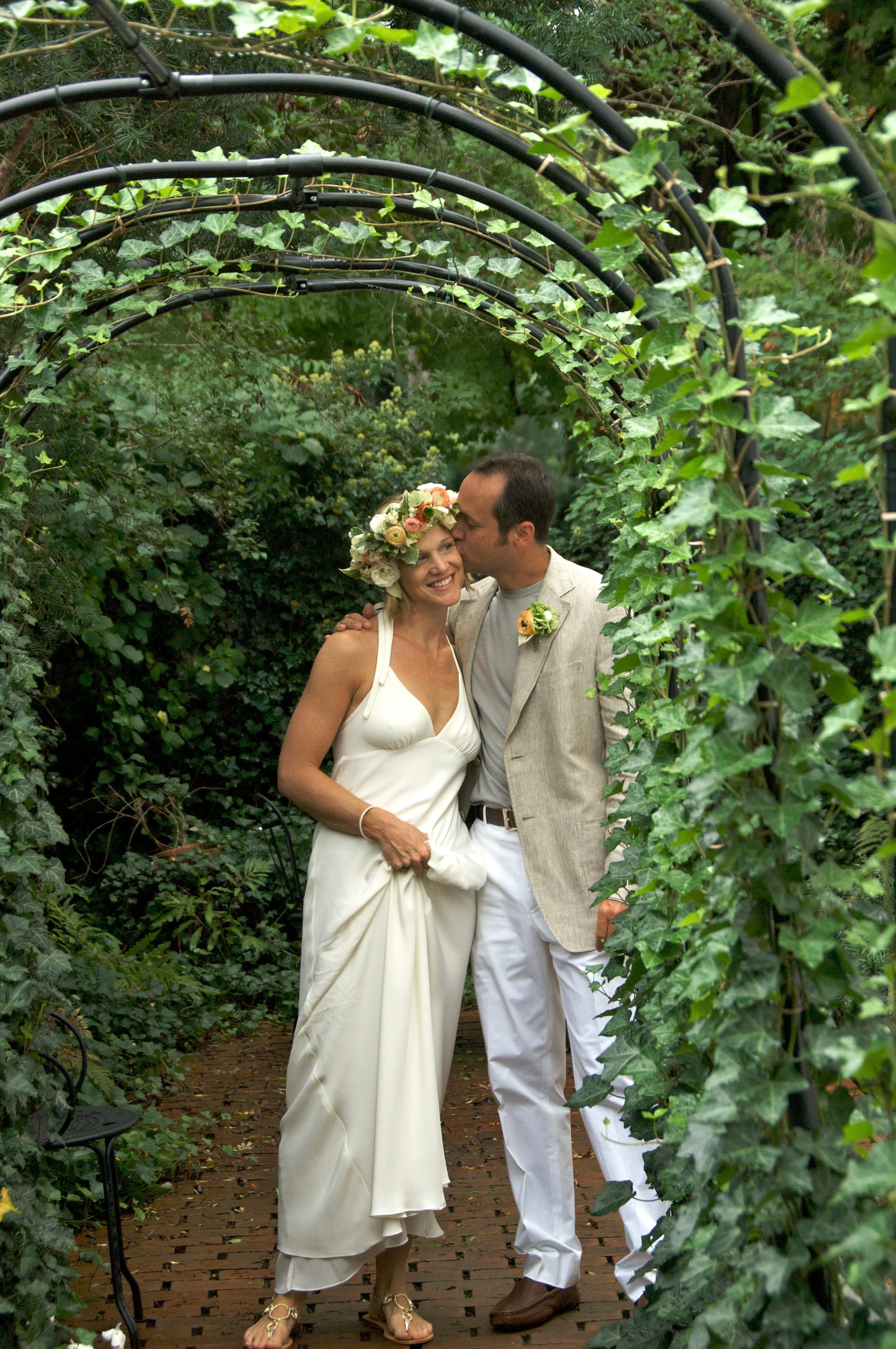 Bride and groom kiss under an ivy trellis by wedding photographer Pamela Einarsen. 