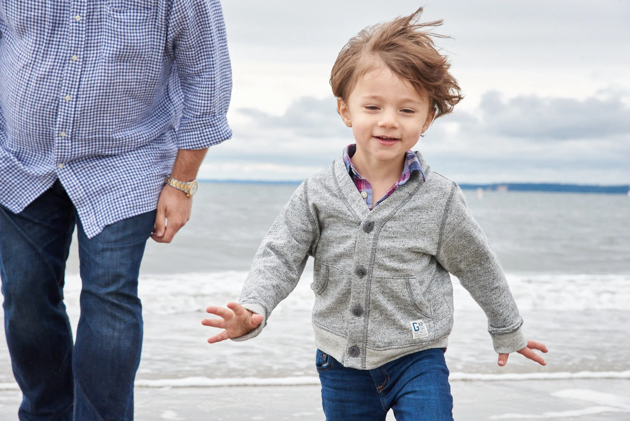 Boy runs on the beach in Old Greenwich, CT with family photographer Pamela Einarsen.
