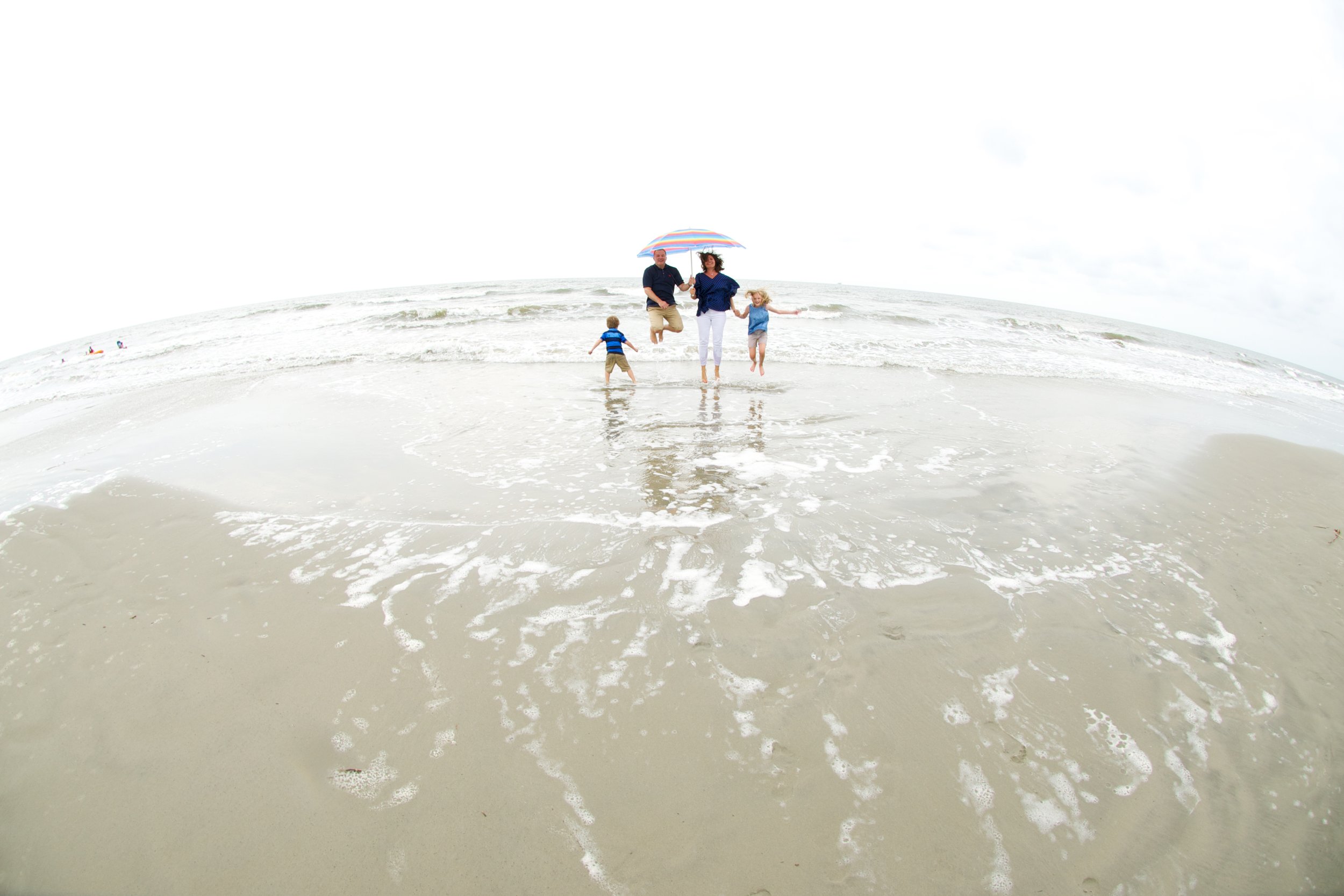 Family stands in the waves on Kiawah by family photographer Pamela Einarsen. 