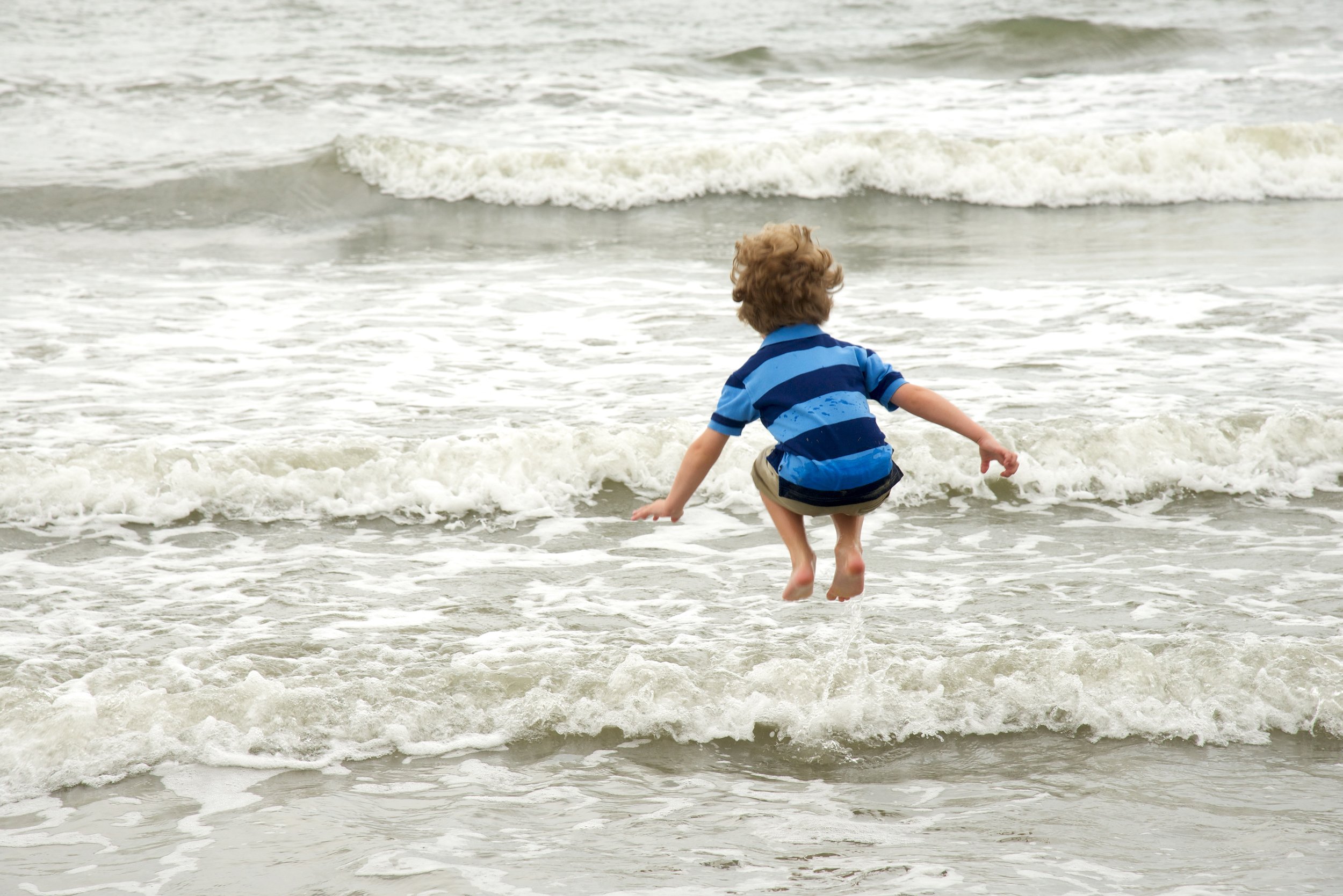 Boy jumps a wave in a candid moment on Kiawah by family photographer Pamela Einarsen. 