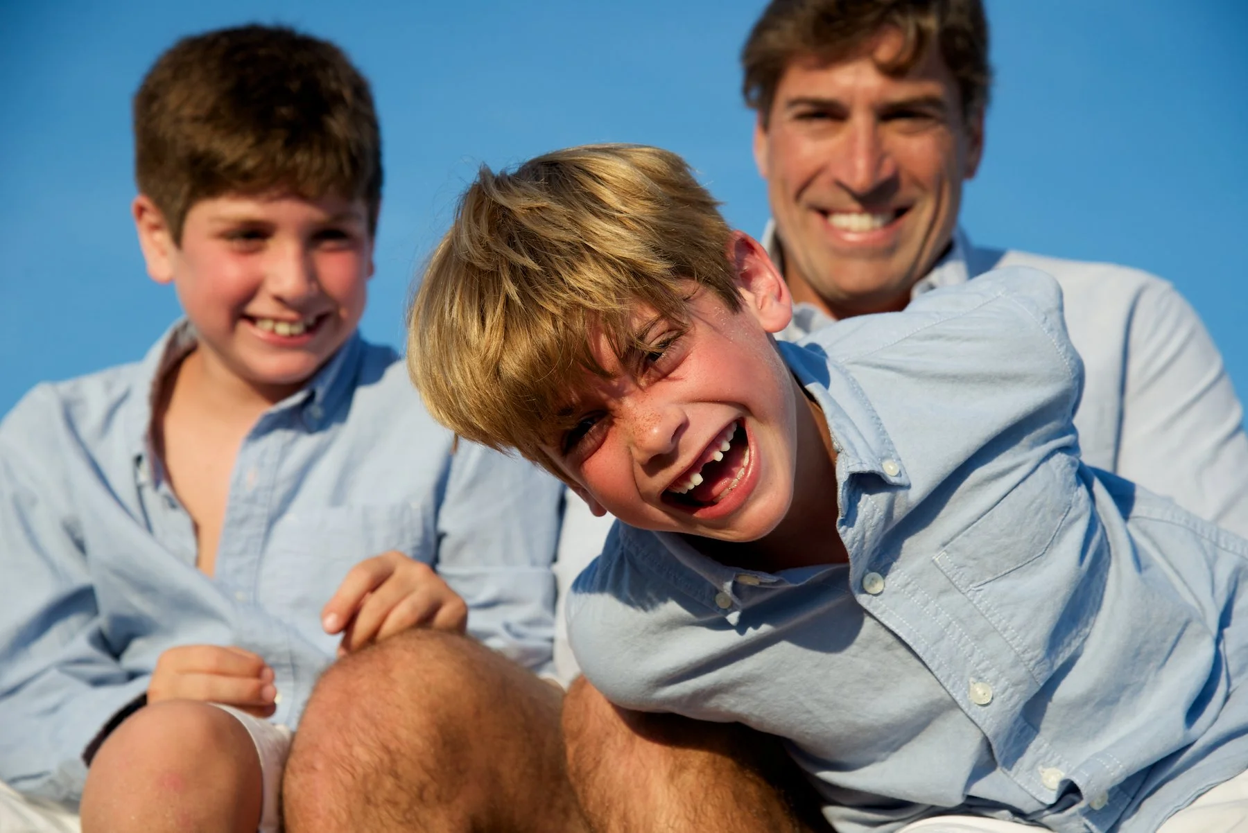 Boys laugh with their father on the New Jersey shore with family photographer Pamela Einarsen.