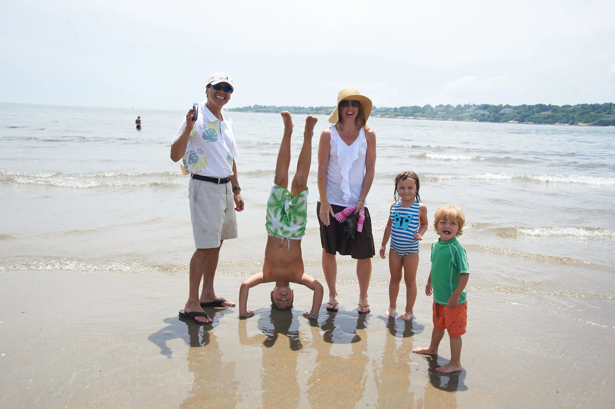 Boy does handstand in the sand with his family in Narragansett photo by family photographer Pamela Einarsen.