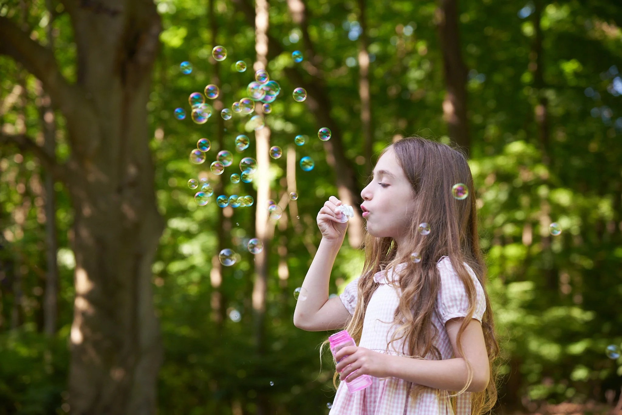 Girl blows bubbles in her Wilton, CT yard with family photographer Pamela Einarsen