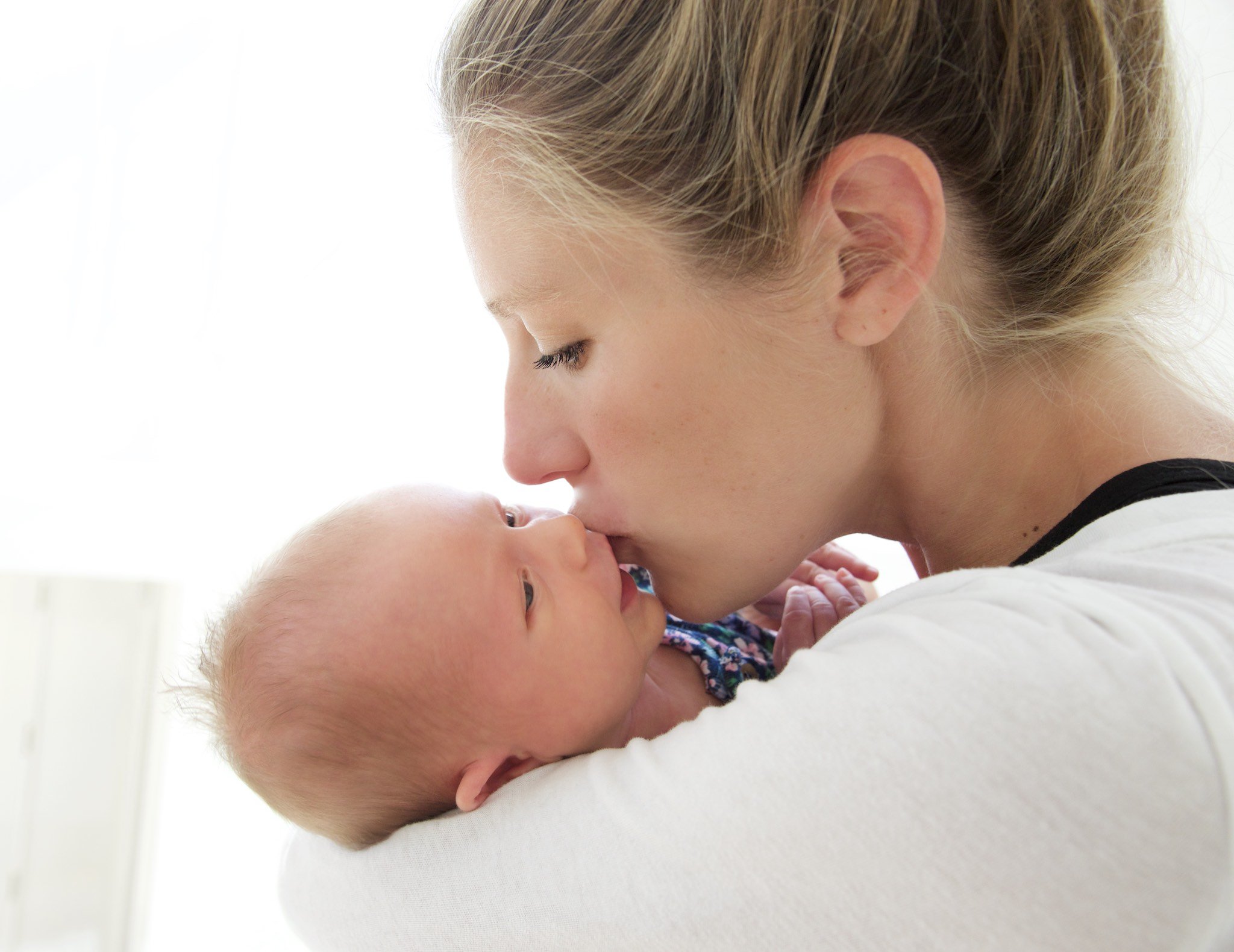 Portrait of mother kissing newborn in Rowayton, CT home by family photographer Pamela Einarsen. 