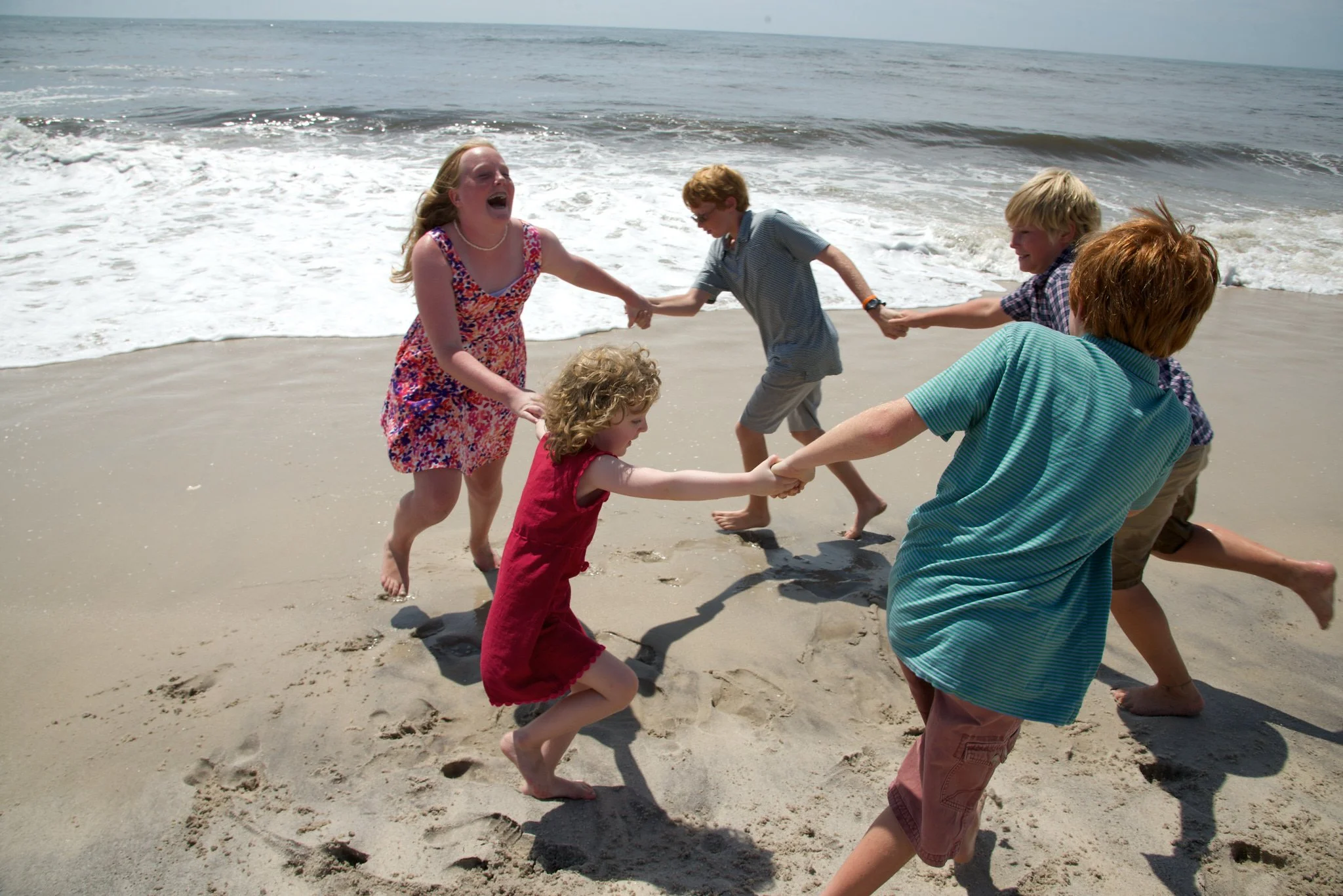 Kids spin in a circle on the beach on Fire Island with family photographer Pamela Einarsen.