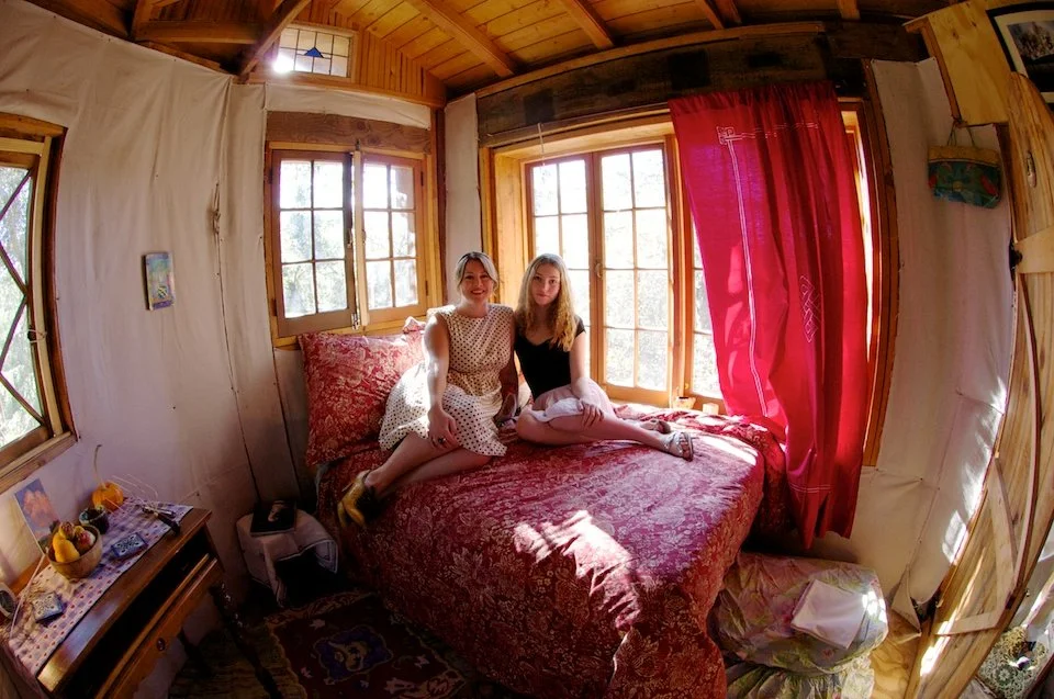 Young women pose on a bed in their Ojia, CA treehouse with lifestyle photographer Pamela Einarsen.