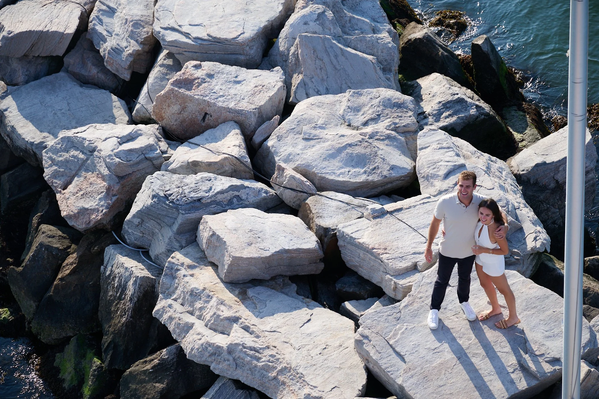  Newly engage couple stand n the rocks of the Green Ledge Lighthouse as proposal photographer Pamela Einarsen gets a Birds Eye view. 