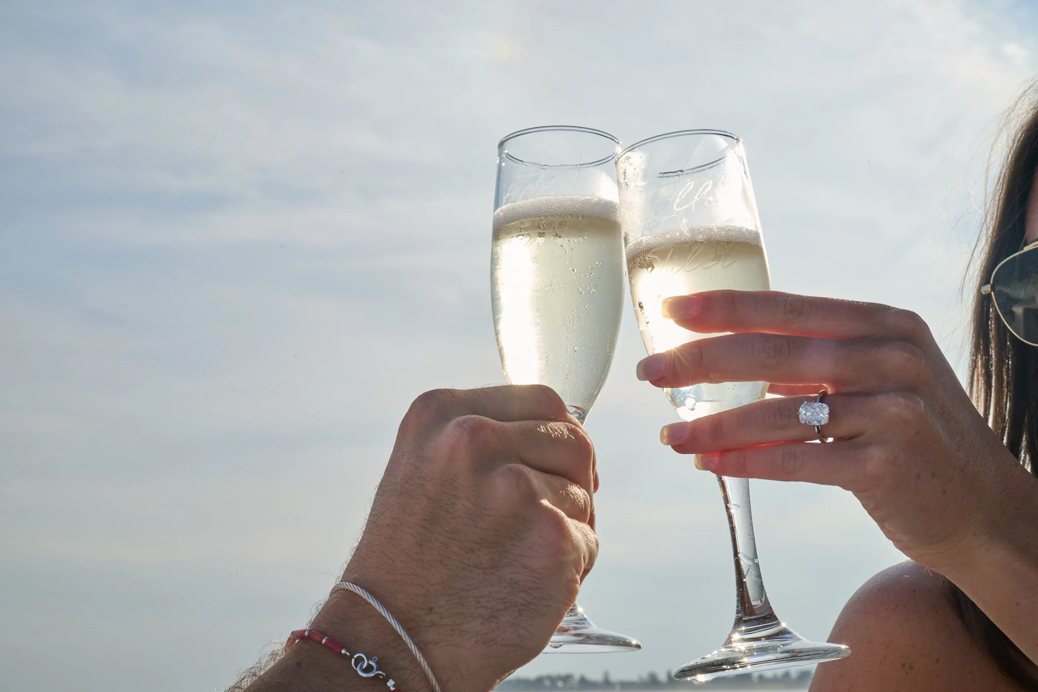 Close up of Champagne toast by engaged couple on boat in Rowayton CT by proposal photographer Pamela Einarsen. 
