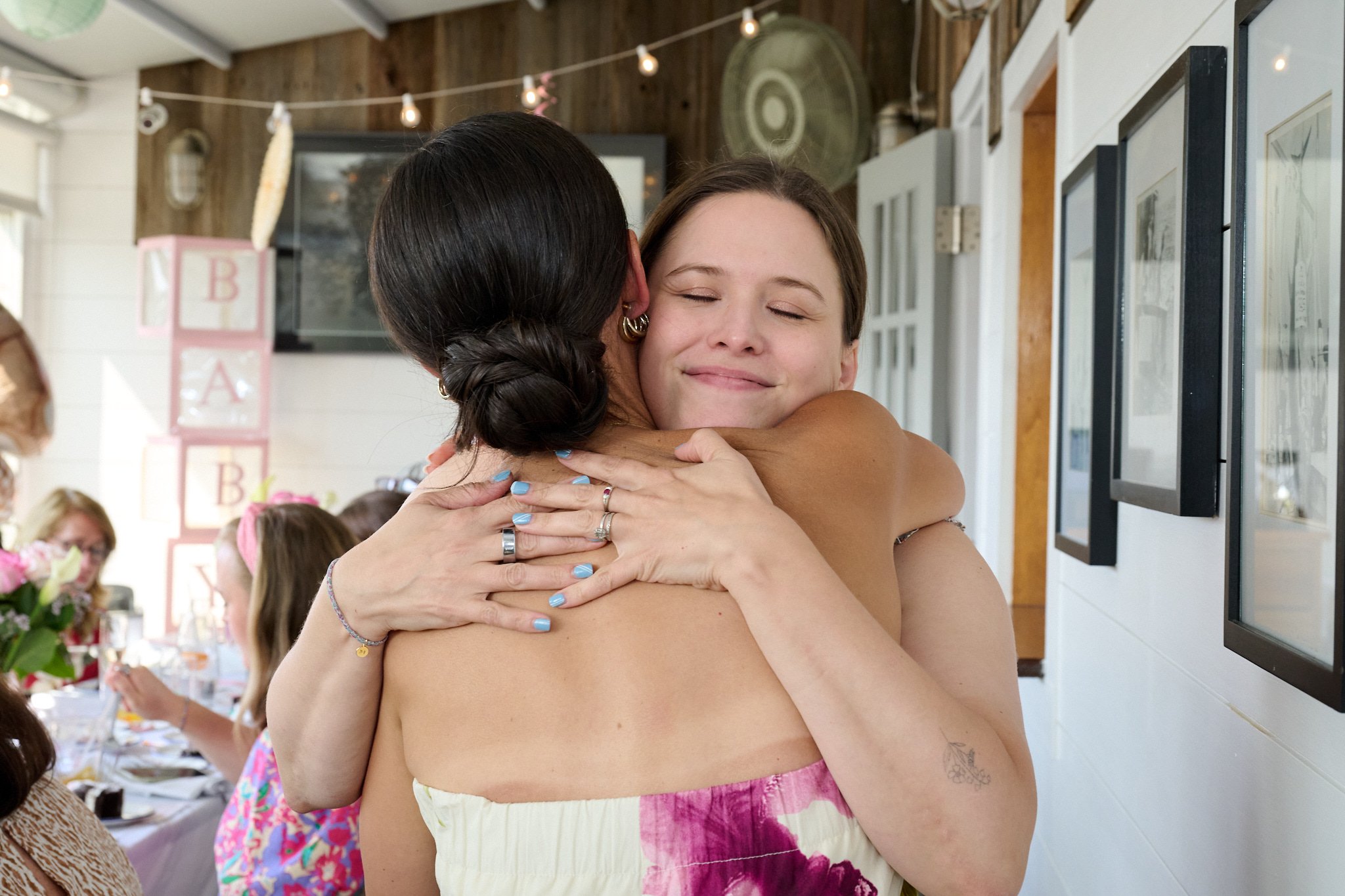 Women joyfully hug at a baby shower photographer by Pamela Einarsen 