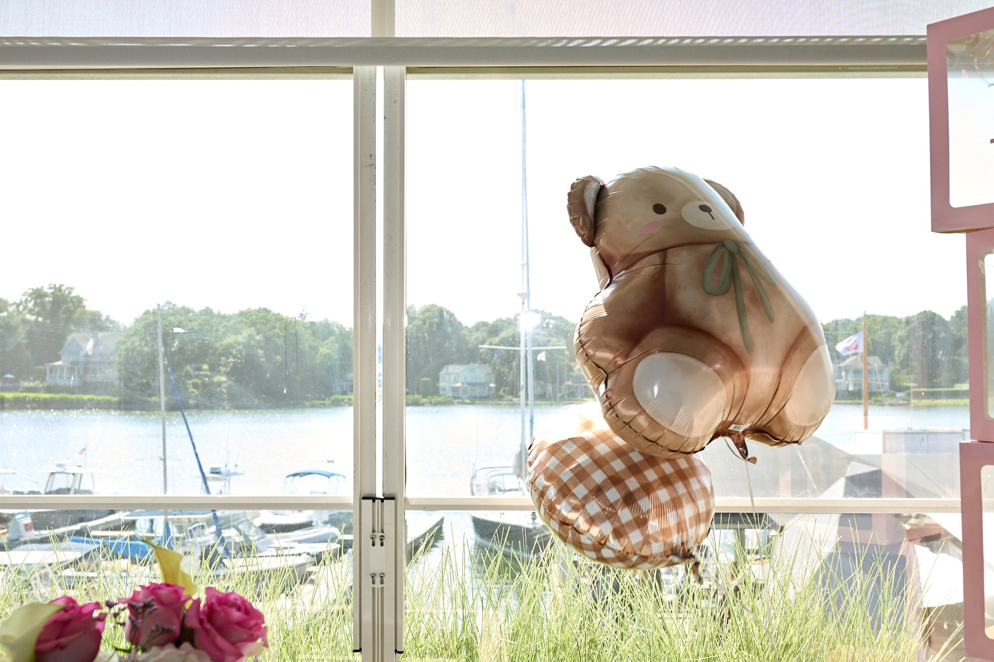 A balloon floats by a window overlooking the water at Rowayton Seafood in CT by baby shower photographer Pamela Einarsen. 